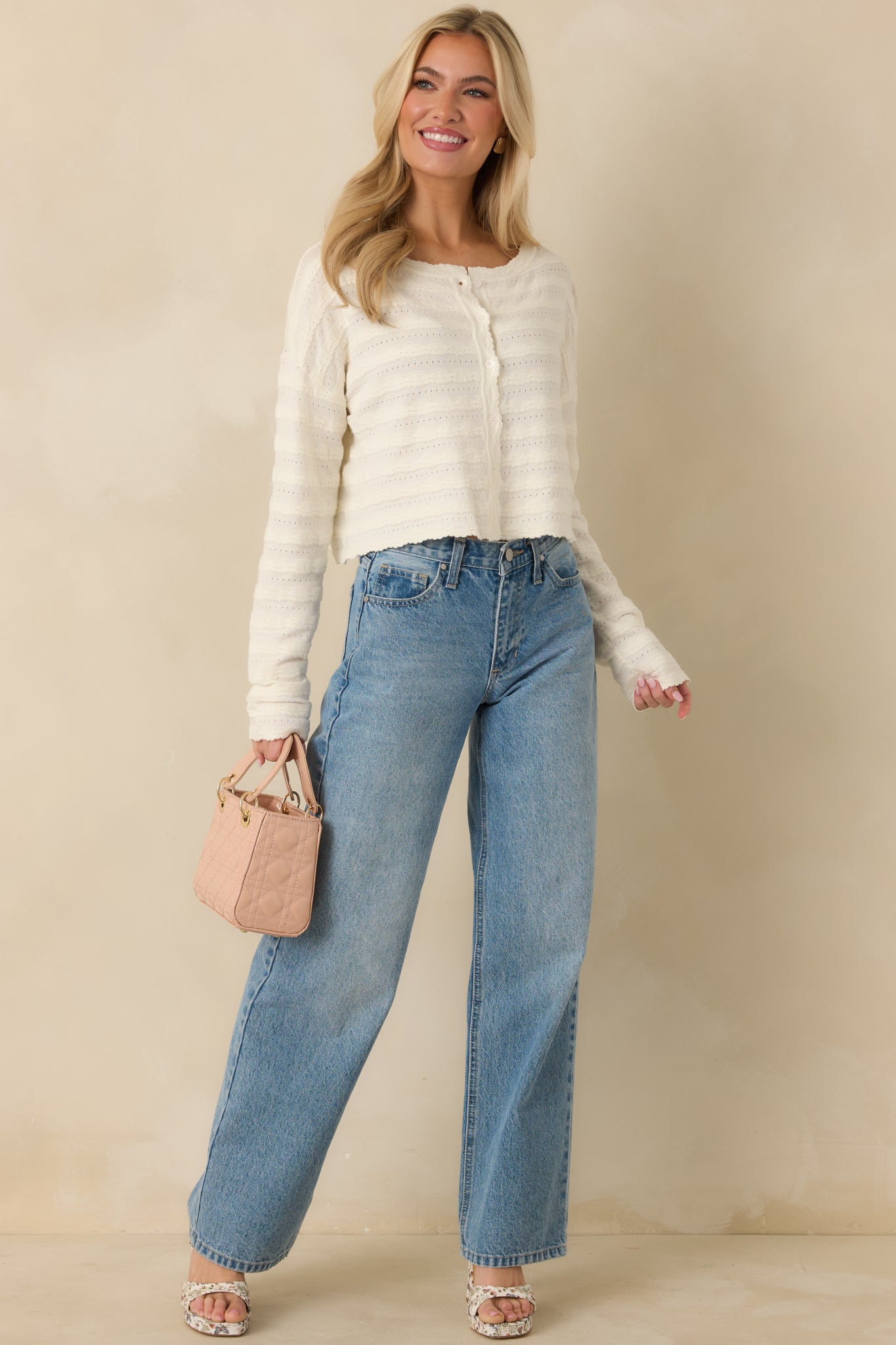 Ivory knit cardigan with long sleeves, delicate scalloped edges, and a refined, polished silhouette.
