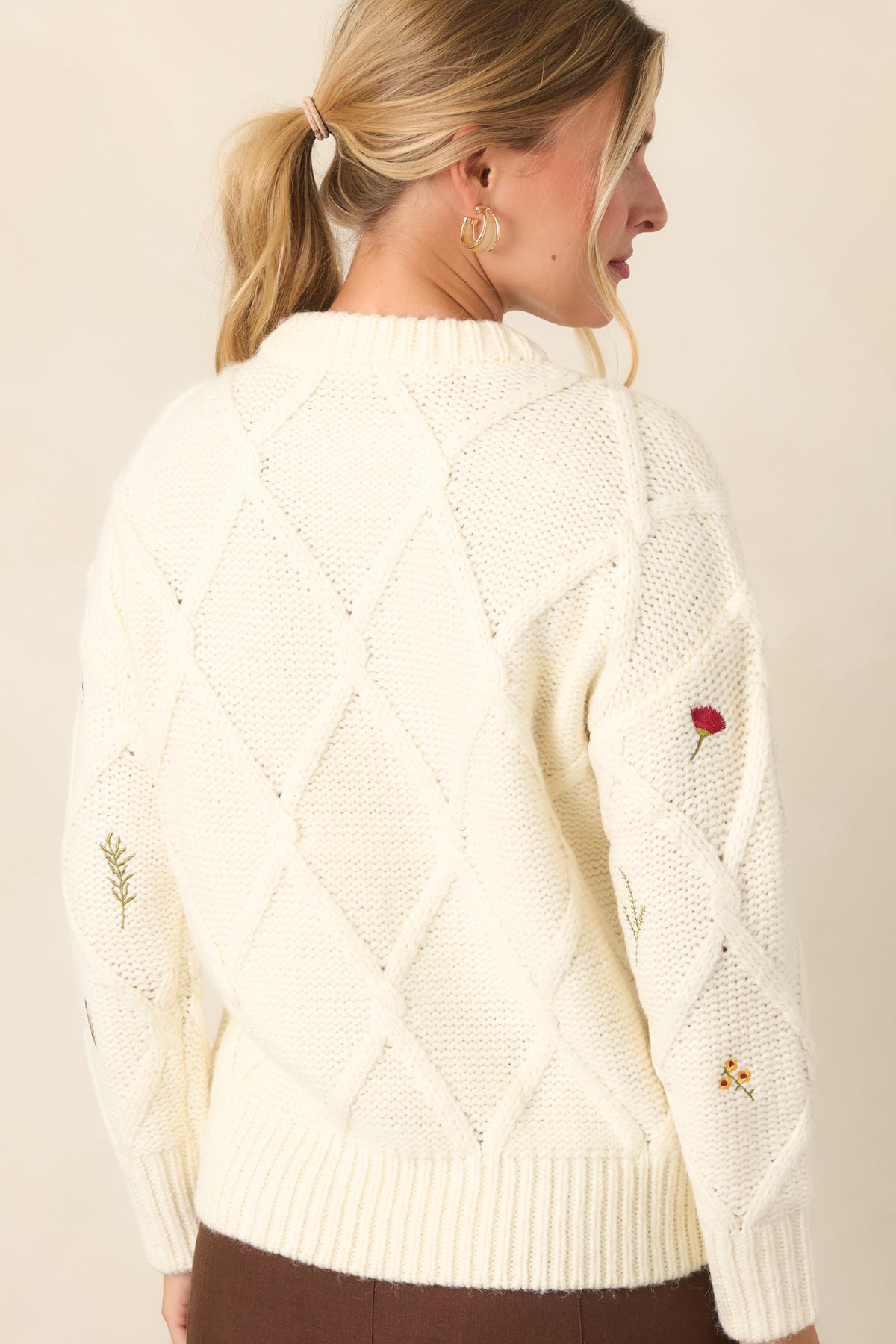 Rear of the ivory knit top showing the raised diamond pattern, long sleeves, relaxed silhouette, and ribbed neckline, cuffs, and hem.