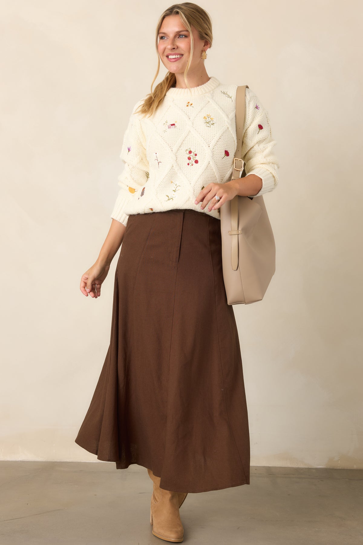 Relaxed ivory knit top with a dimensional diamond texture, colorful embroidered garden motifs, crew neckline, long sleeves, and ribbed hem.