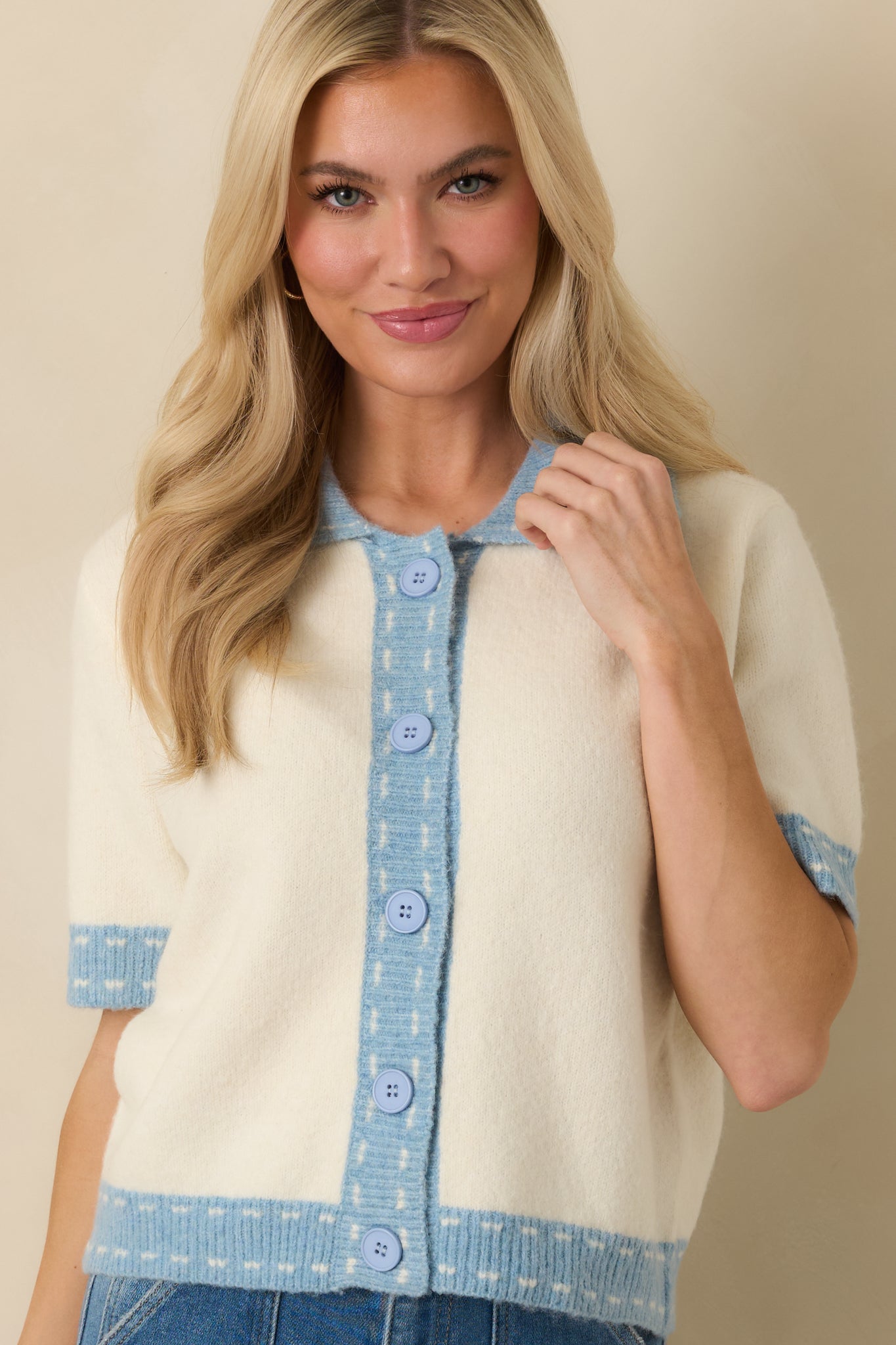 Ivory knit texture framed by light blue contrast trim along the collar and button placket.
