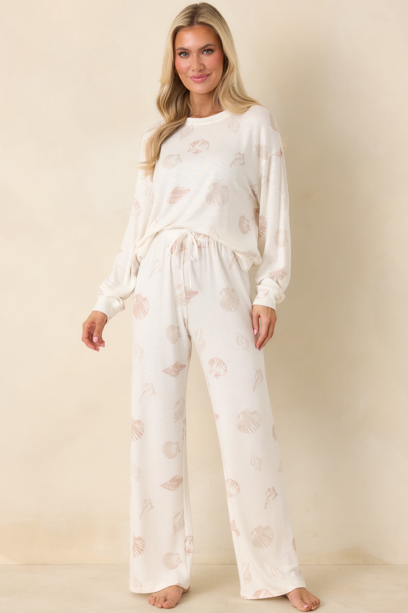 Relaxed ivory knit pullover with classic crew neckline, ribbed trim, and scattered neutral shell motif.