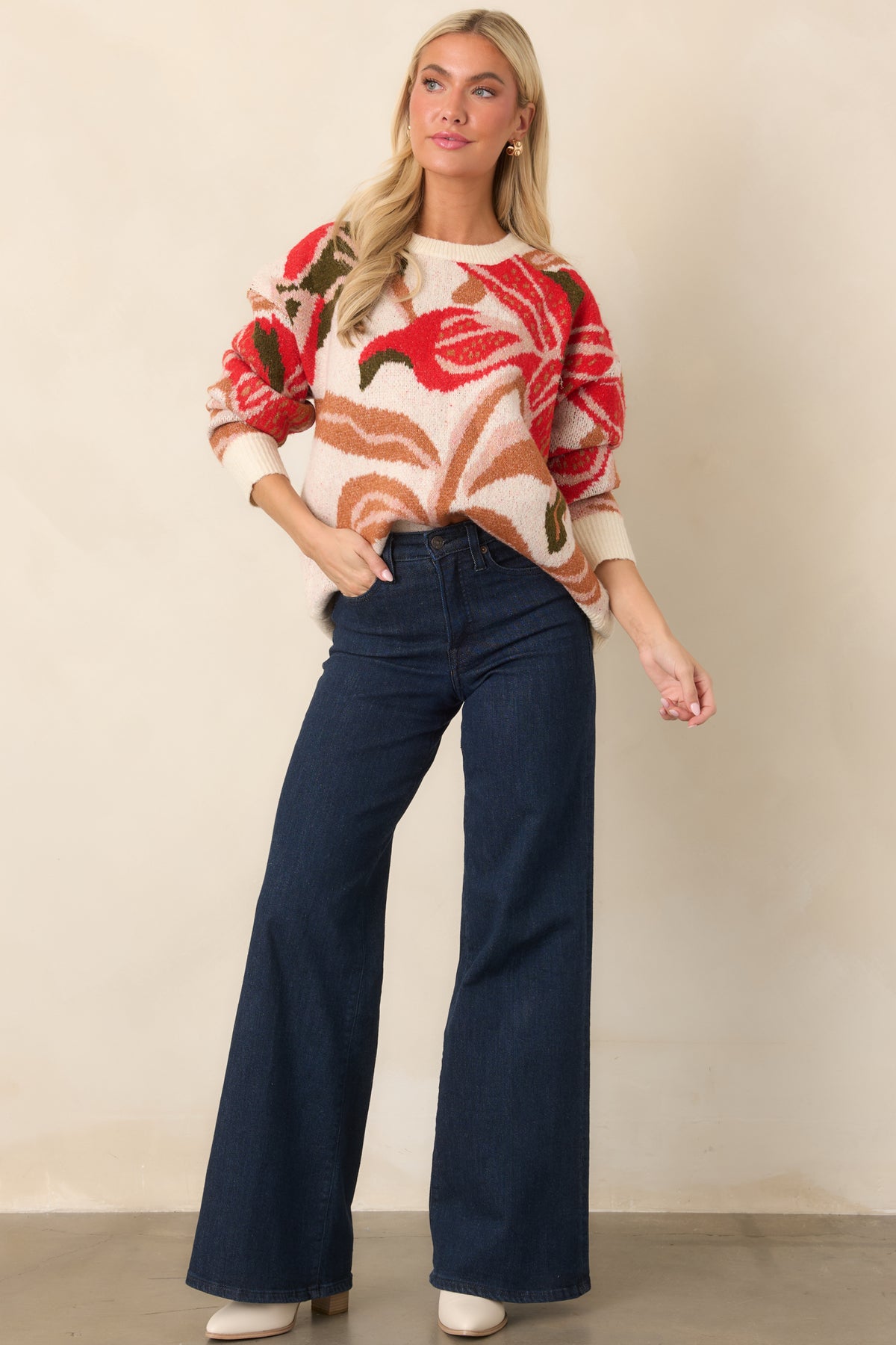 Relaxed ivory knit top showcasing bold red floral blooms, dropped shoulders, long sleeves, and ribbed trim.