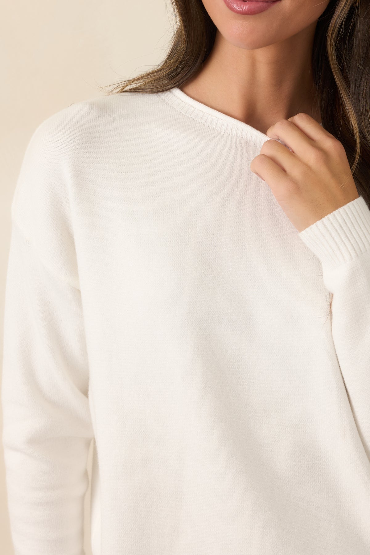 Close view of the ivory knit fabric and ribbed trim along the cuff and hem.