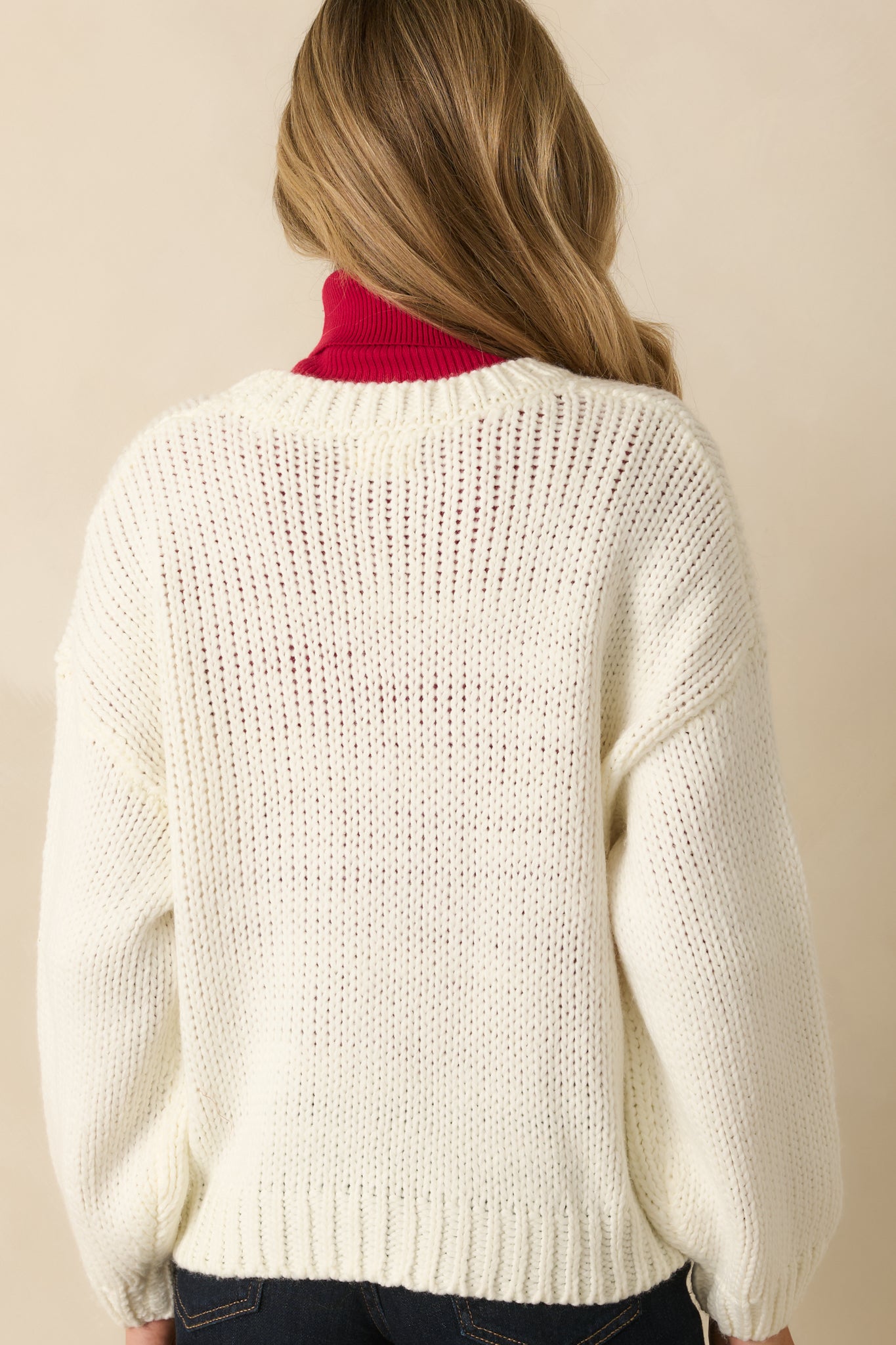 Rear view of ivory knit sweater showing plain back design and ribbed trim.