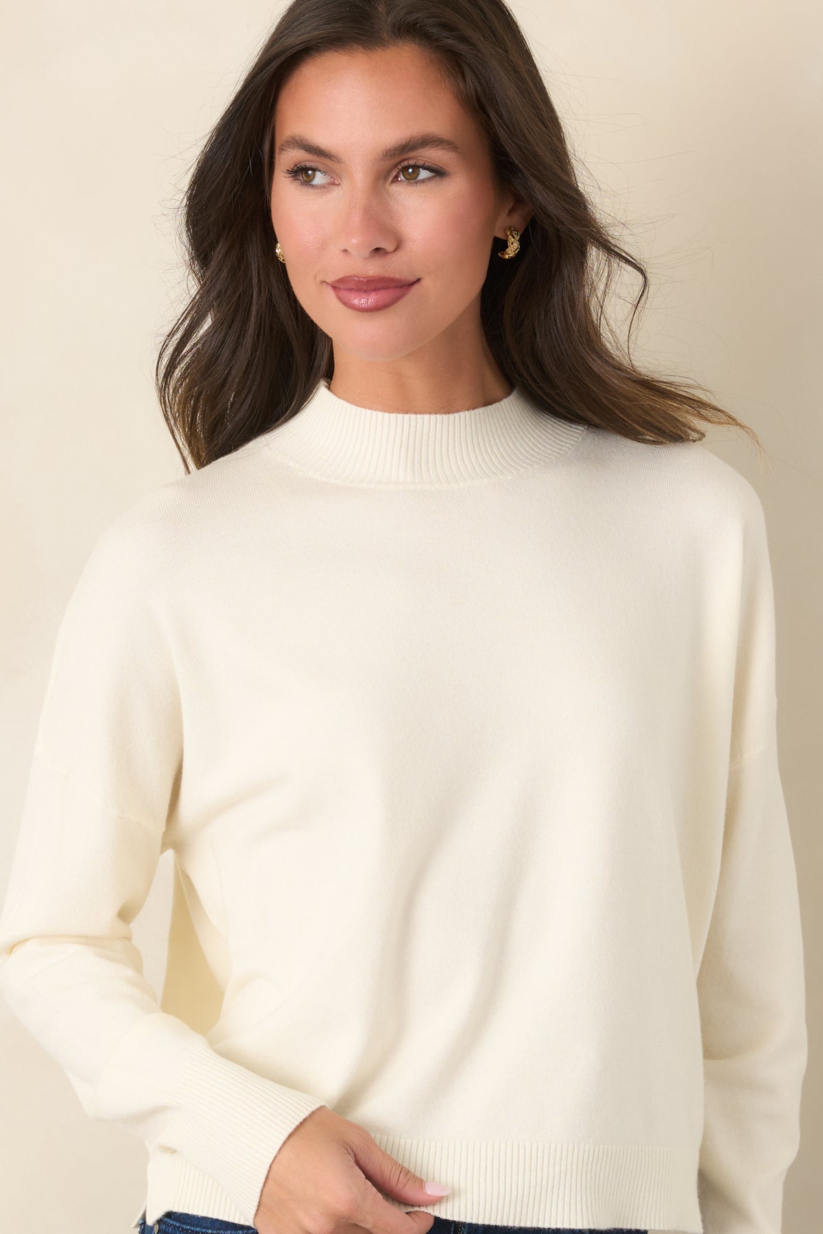 Smooth ivory knit top with a relaxed front, long sleeves, and coordinated ribbed neckline and cuffs.