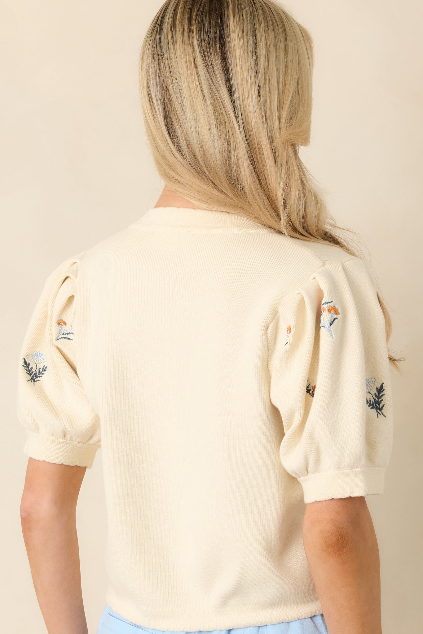 Ivory knit top with short sleeves and clean, relaxed silhouette from the rear view.