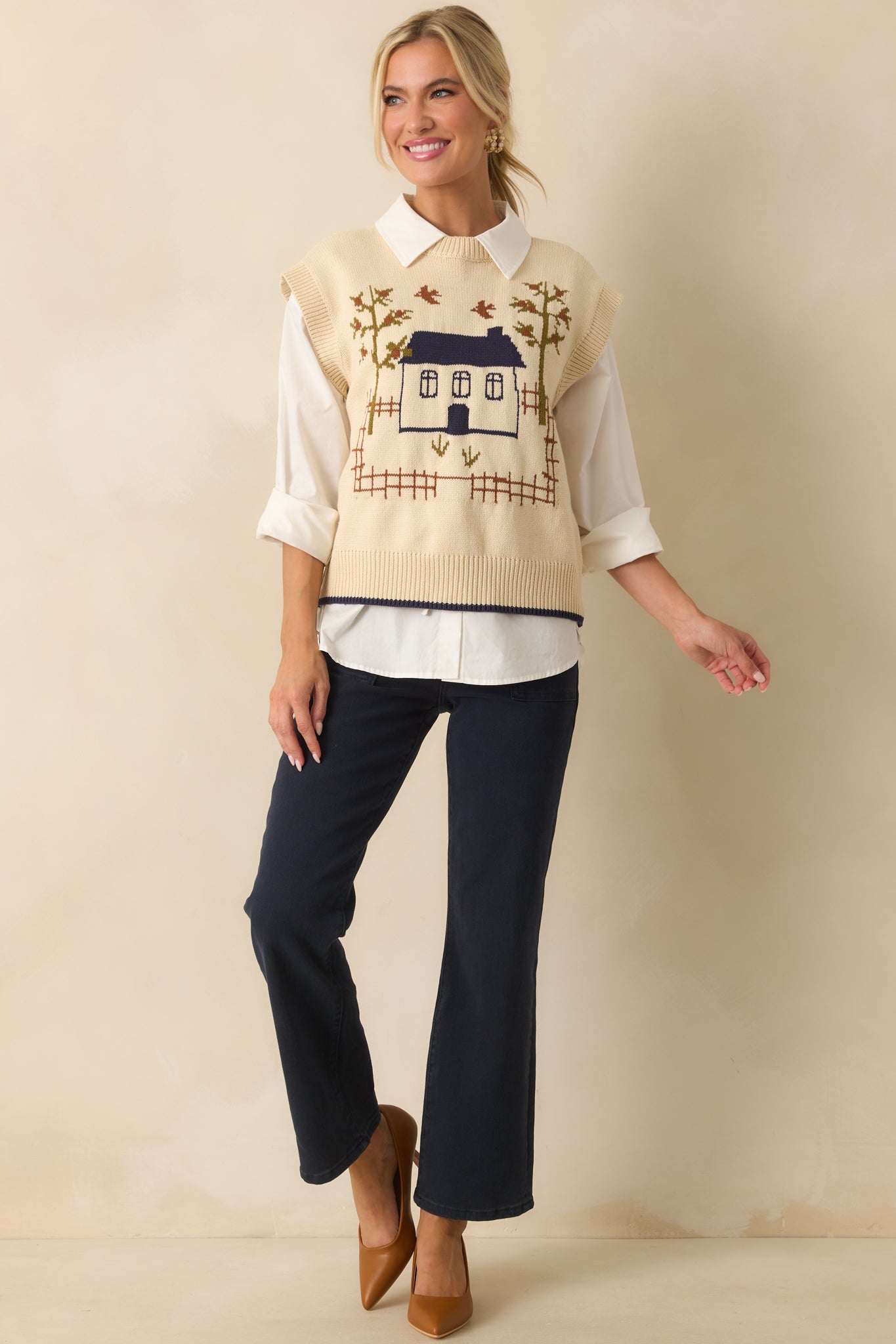 Front view of ivory knit vest highlighting the whimsical house and tree design.