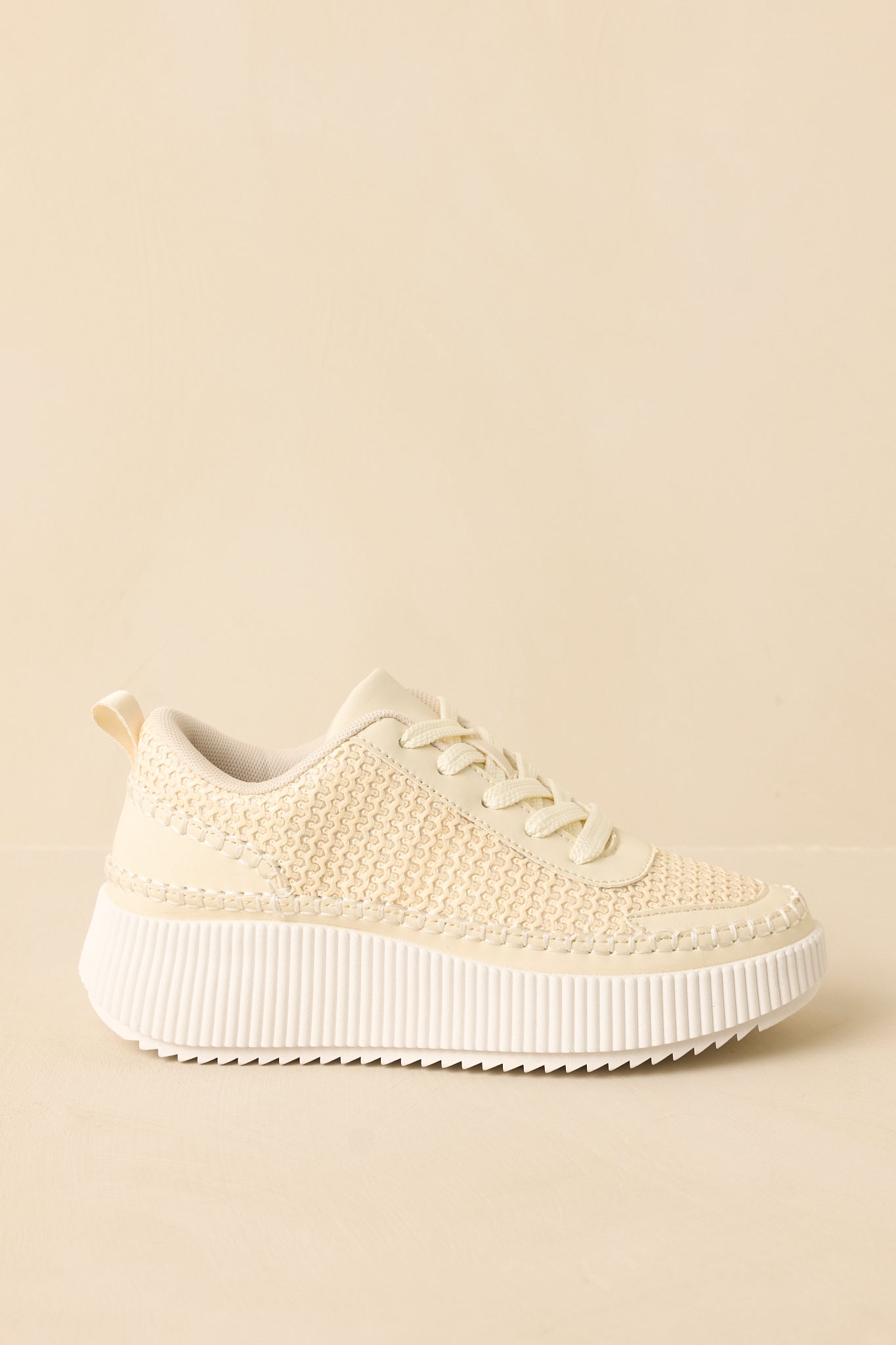 Ivory lace-up sneakers displaying the full side profile and textured outsole edge.