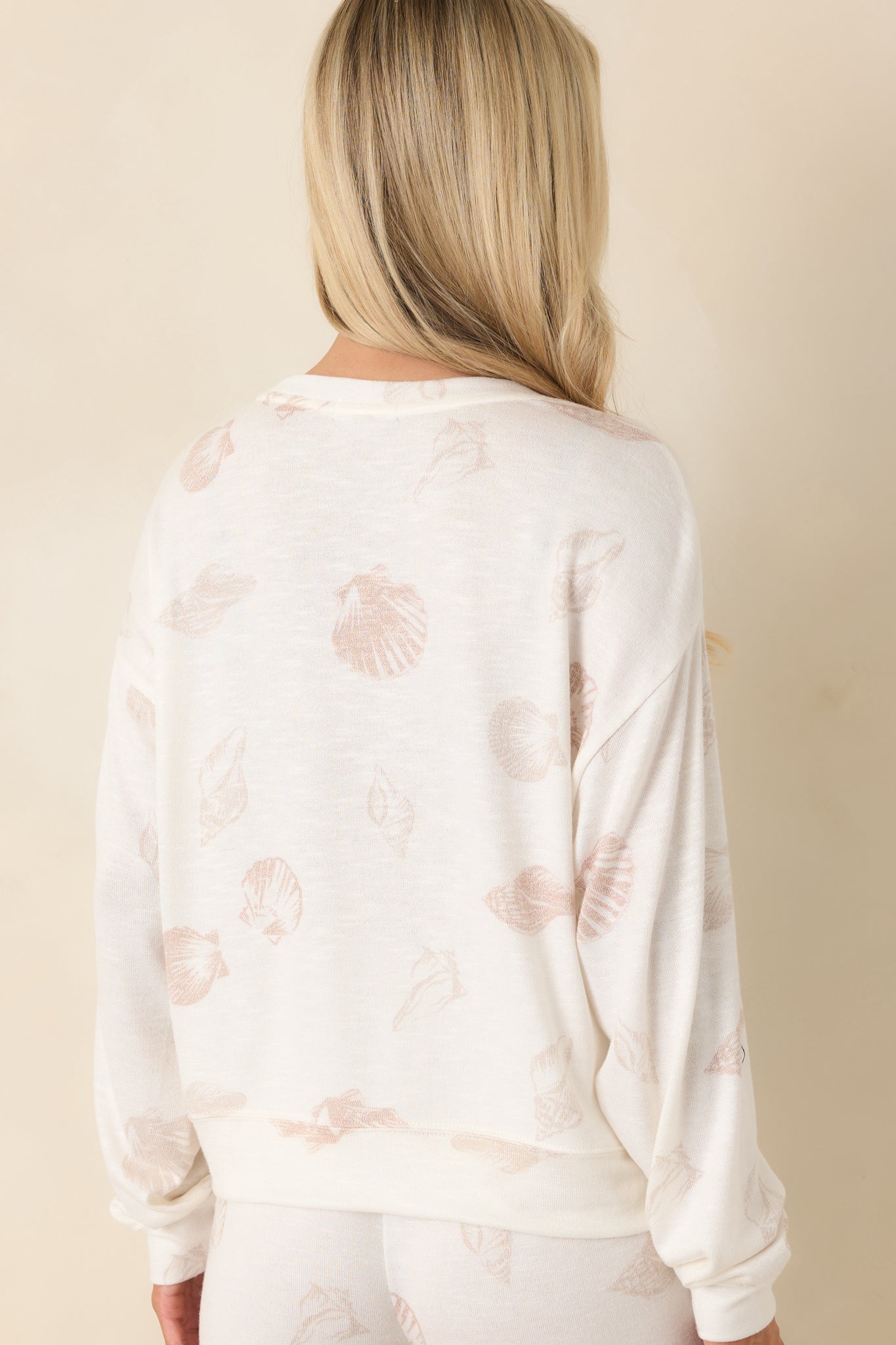 Rear view of ivory long sleeve knit top featuring relaxed silhouette, drop shoulders, and ribbed hemline.