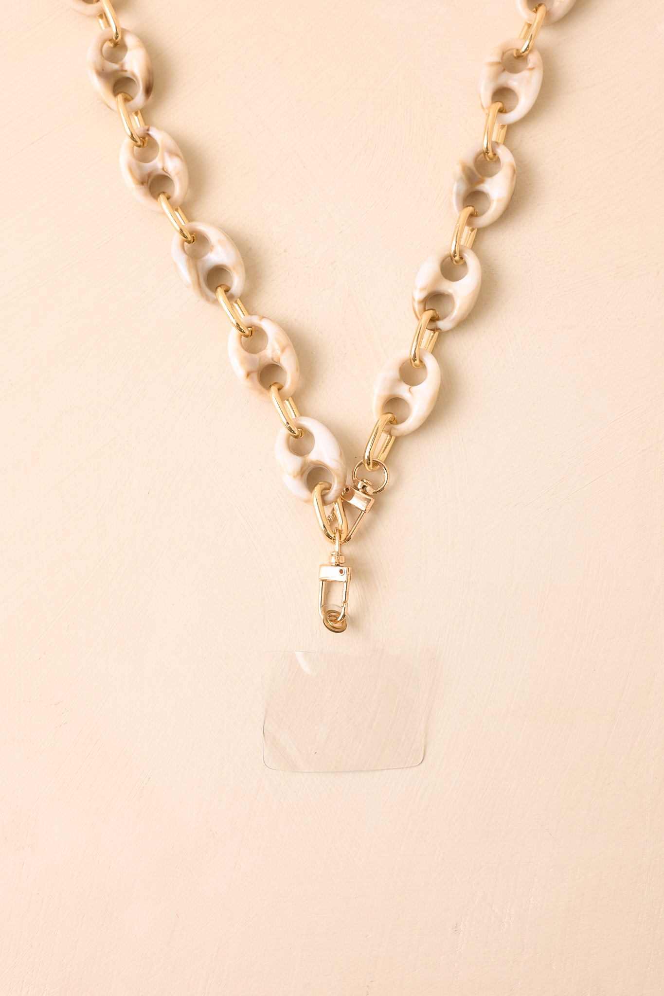Detailed view of the phone lanyard, emphasizing the swirling ivory marbled resin texture, connected links, and gold-tone hardware.