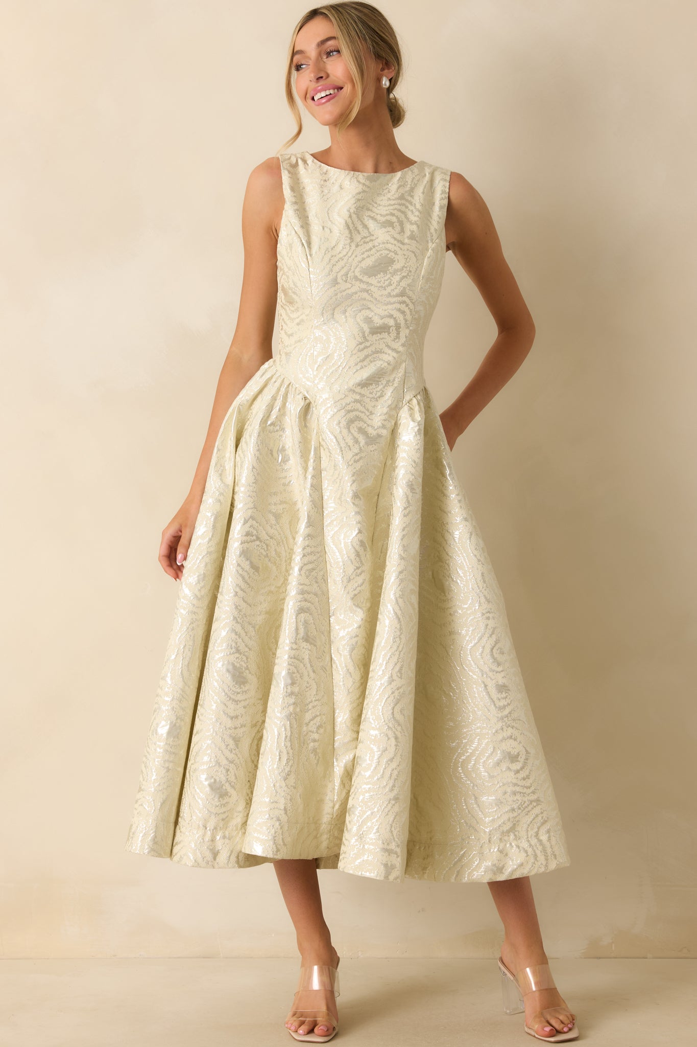 Ivory metallic jacquard midi dress featuring a sleeveless bodice, high scoop neckline, and full pleated skirt.