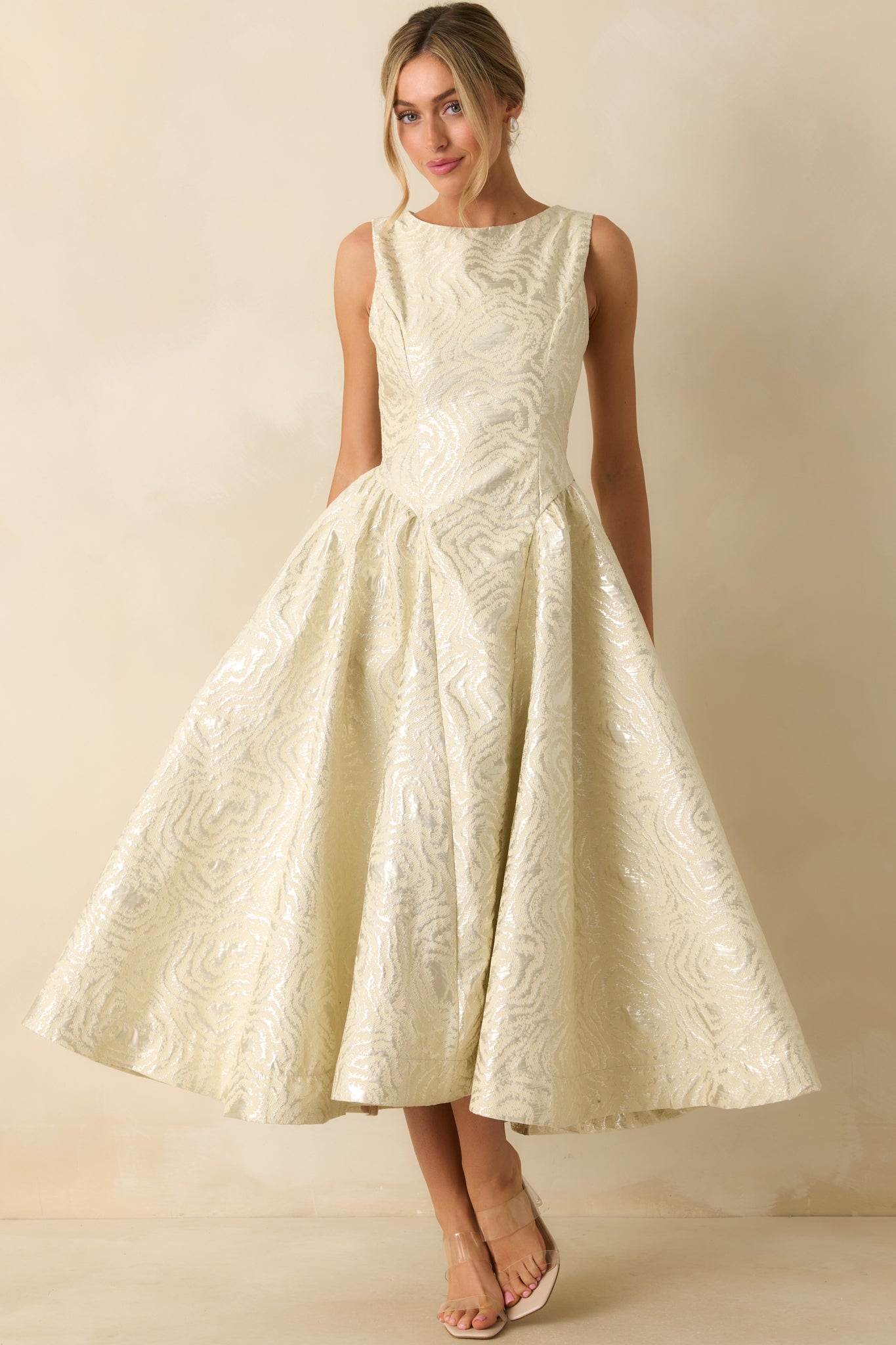 Ivory metallic jacquard midi dress shown with a sleeveless bodice, defined waistband, and flowing pleated skirt for a structured, elegant silhouette.
