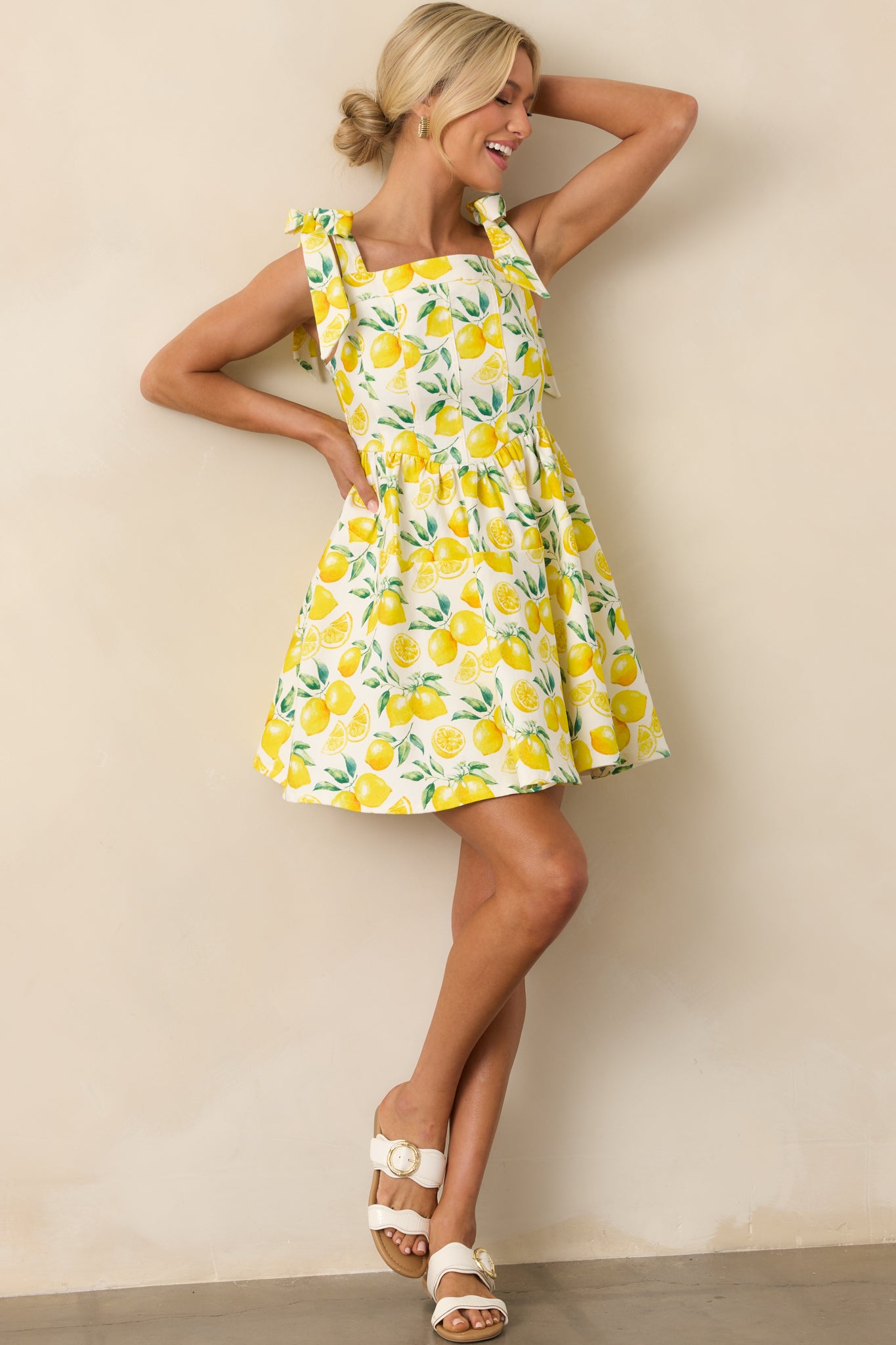 Ivory mini dress with a yellow lemon print, featuring a square apron neckline and drop waist, shown in a full body front view.