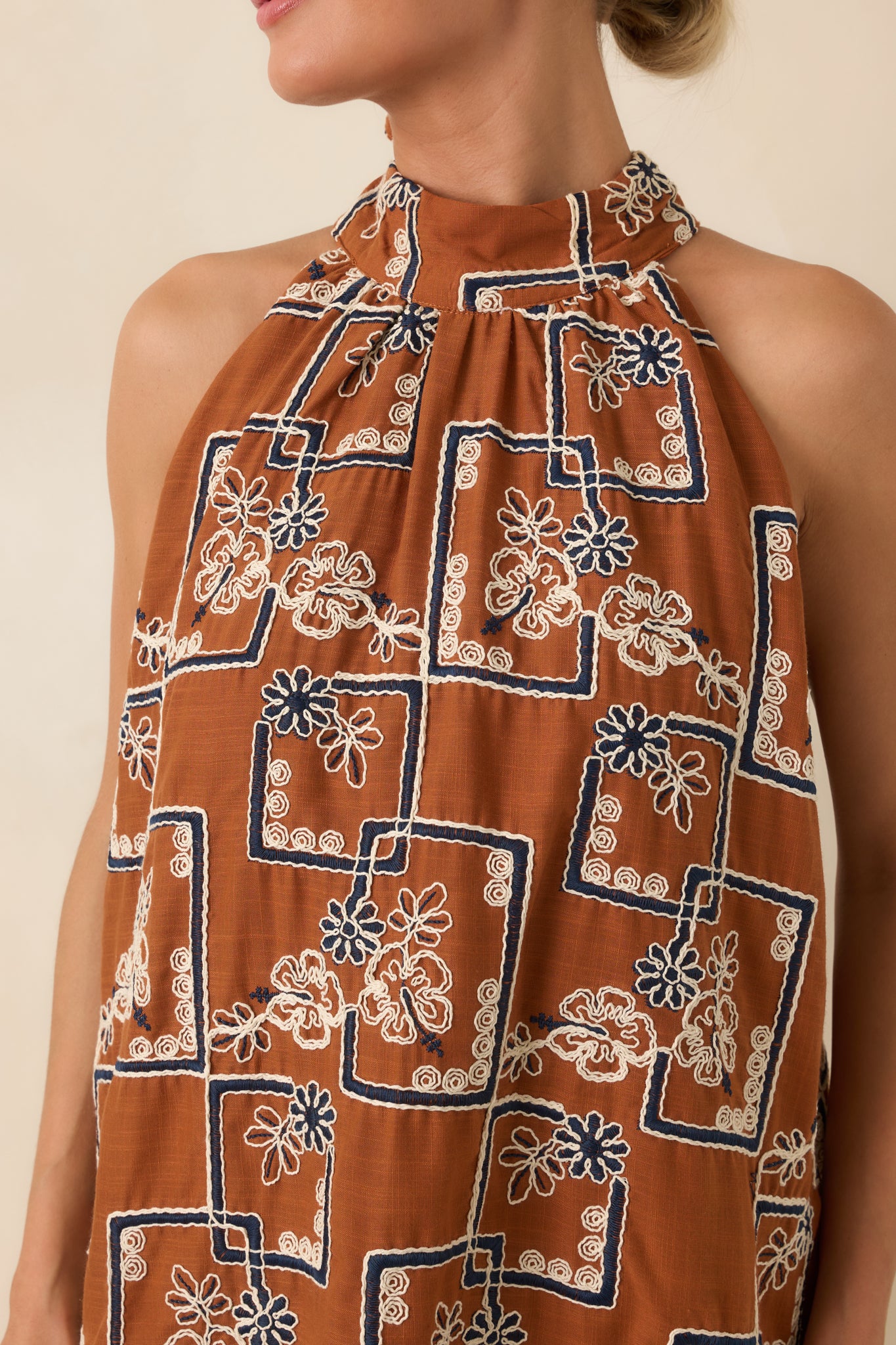 Close-up detail of the ivory and navy embroidery, halter tie, and textured fabric.