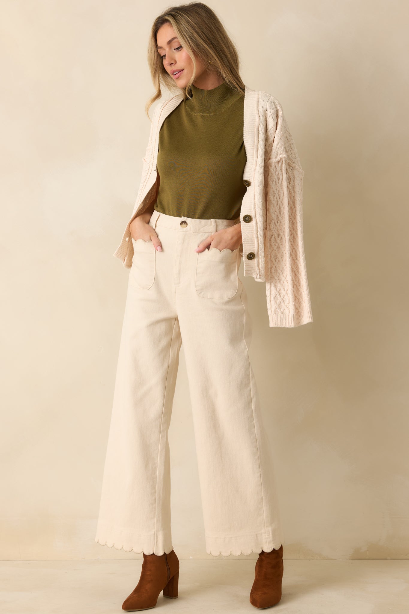 Ivory pants with belt loops, wide-leg silhouette, and scalloped details at hem and front pockets for an elevated finish.