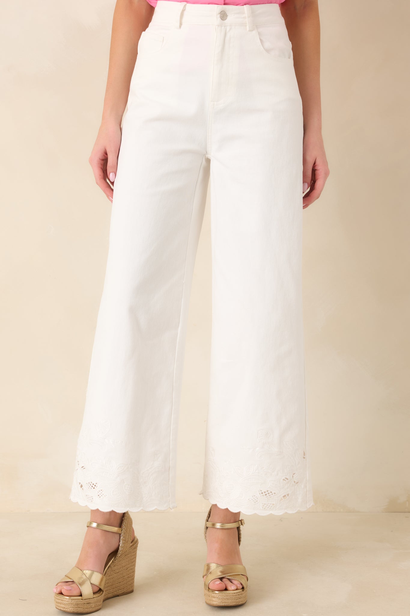 Detailed front view of the ivory pants emphasizing the embroidered lace hem and scalloped edge finish.
