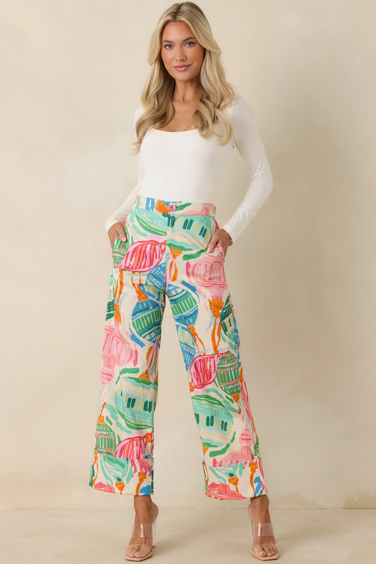 Wide-leg printed pants with pink, orange, blue, and green motifs against an ivory background.