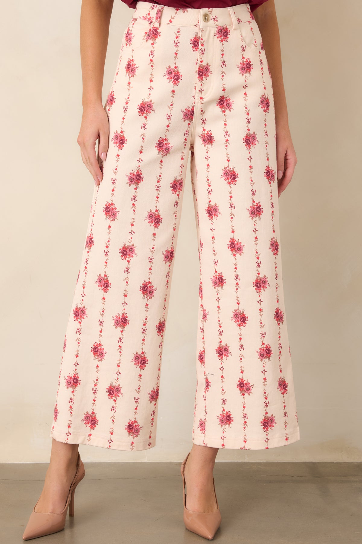 Detailed view of the ivory pants featuring romantic floral motifs arranged in elongated vertical patterns across the fabric.
