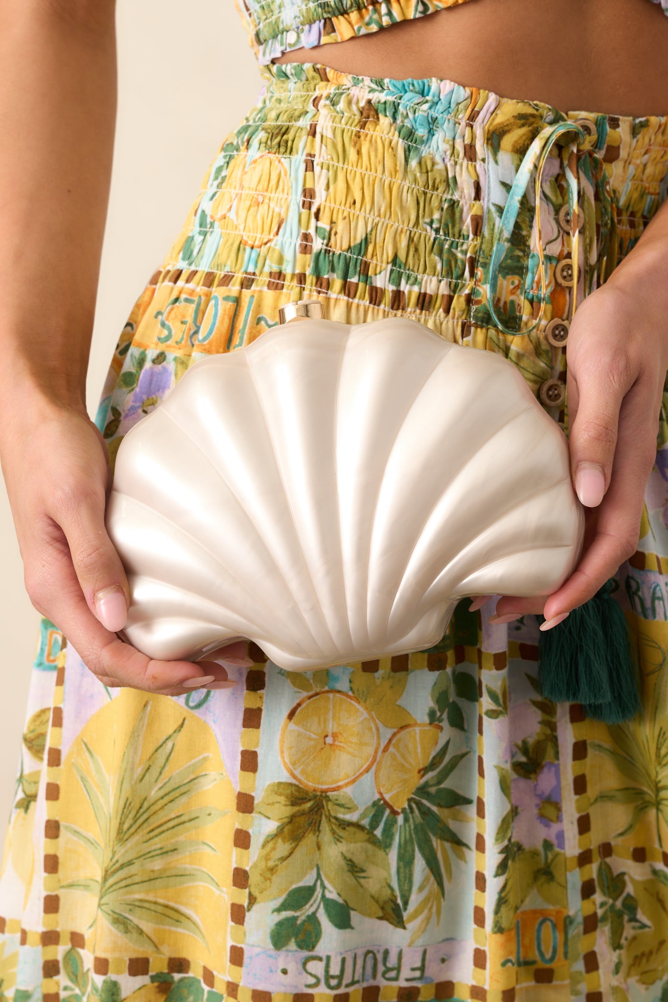 Detailed view of the ivory pearlescent finish and seashell shape of this clutch, with its magnetic clutch closure and the optional crossbody chain for both style and practicality.