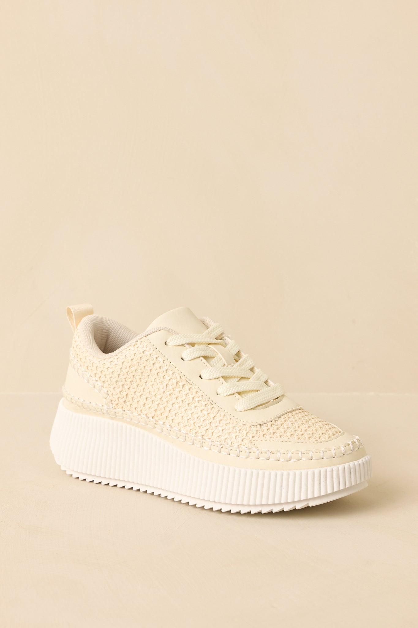 Ivory platform sneakers angled to highlight the cushioned insole and flexible knit texture