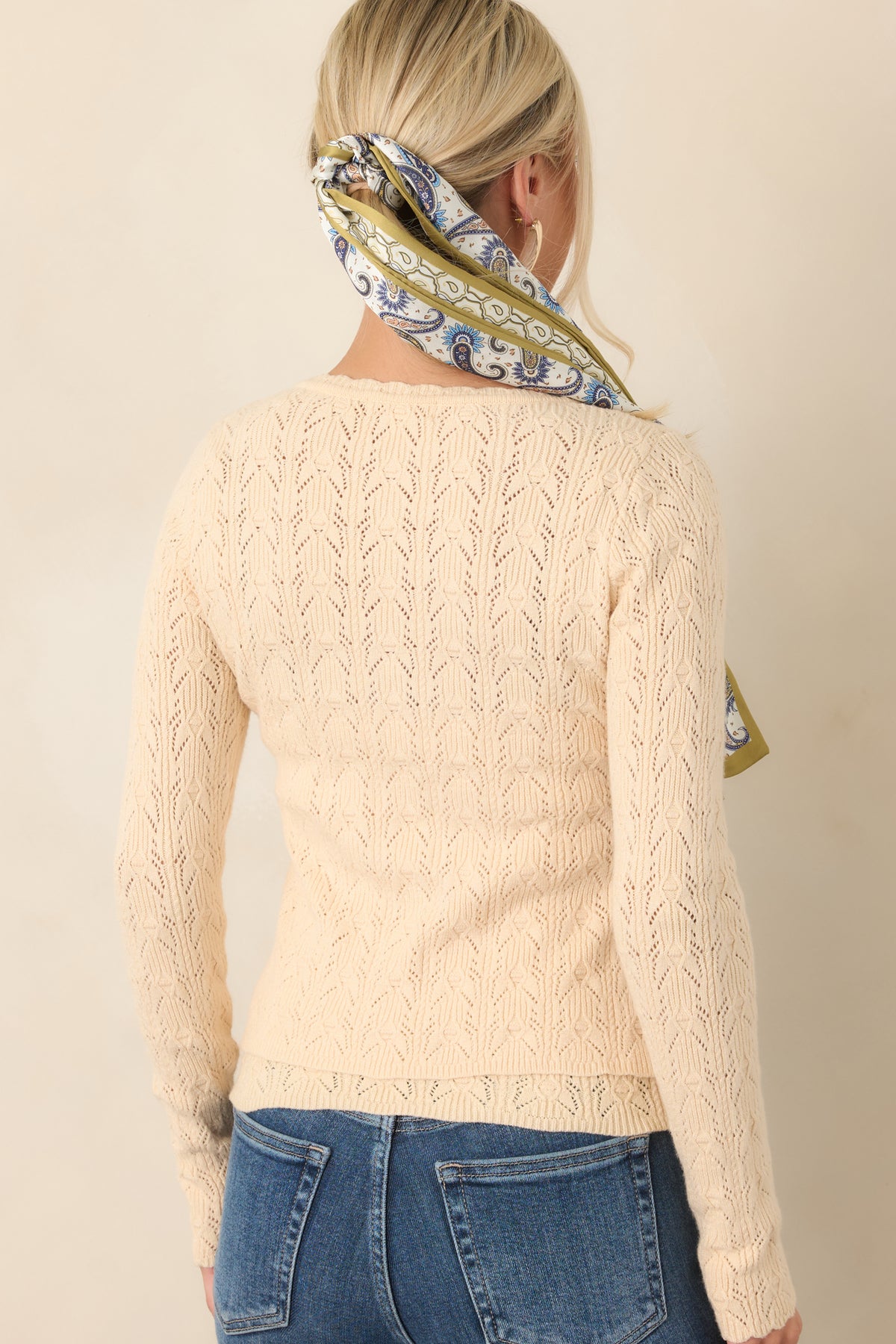 Rear view of the ivory pointelle cardigan showcasing its openwork knit texture, long sleeves, cropped length, and clean back construction.