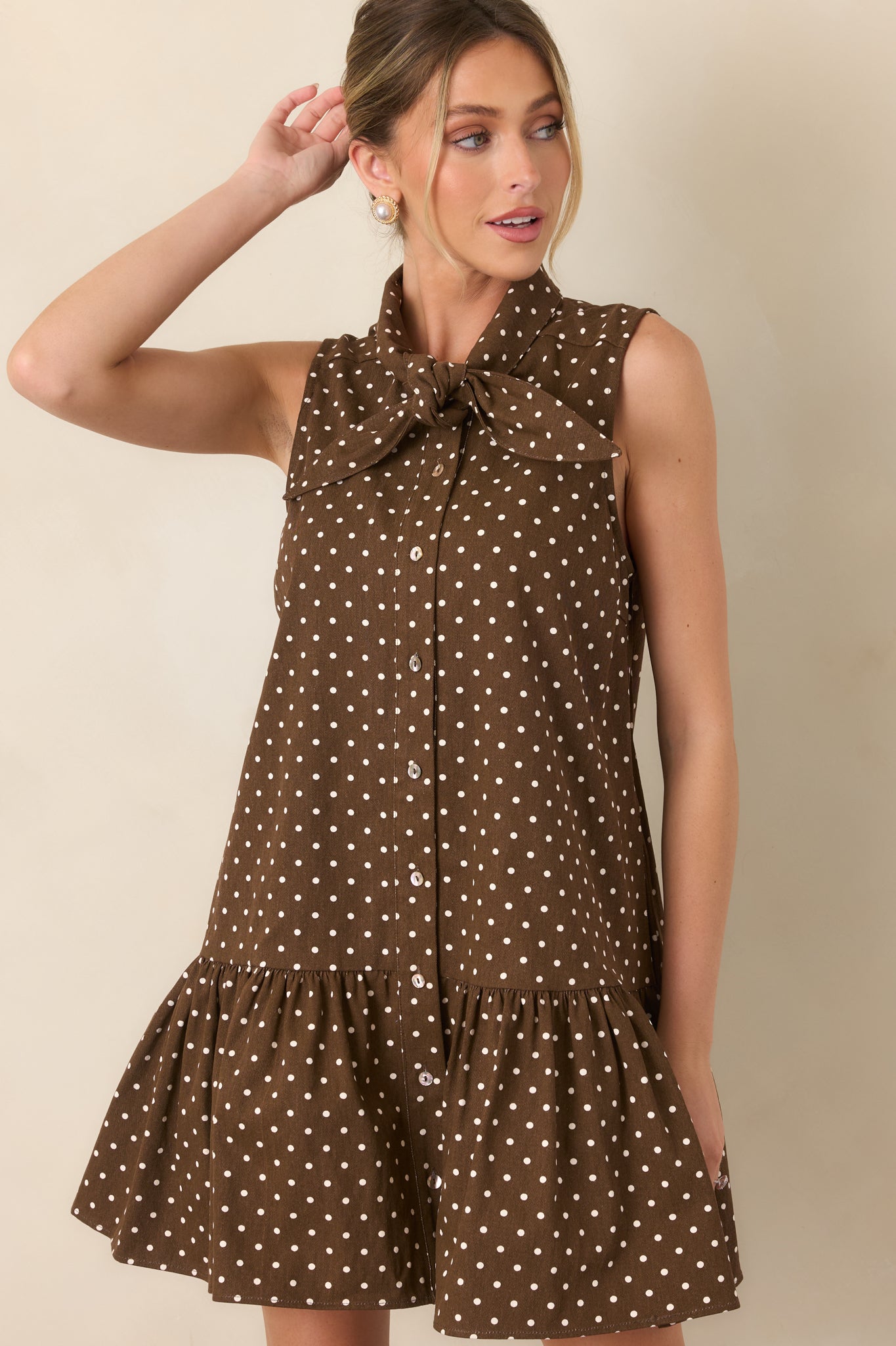 Detailed view of the ivory cotton fabric and polka dot pattern across the sleeveless bodice, accented by a row of buttons.