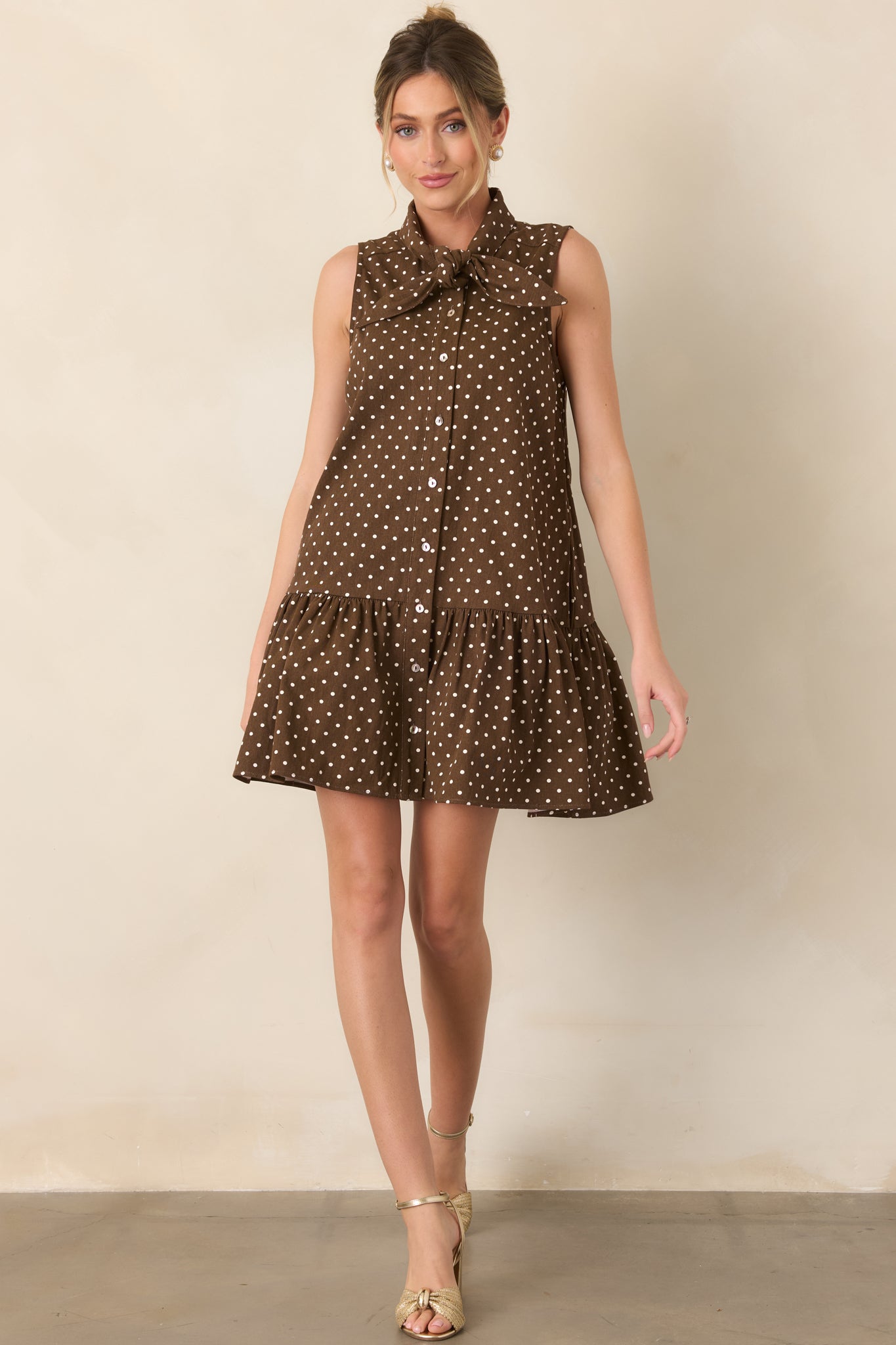 Ivory cotton mini dress showcasing a relaxed shape, self-tie neckline, side pockets, and a voluminous gathered ruffle hem.