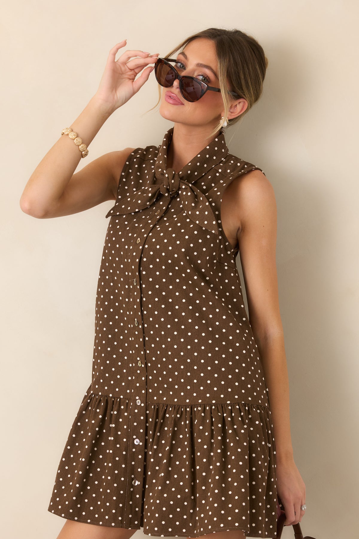 Ivory polka dot cotton dress highlighting the self-tie neckline, button-front closure, and relaxed sleeveless bodice.