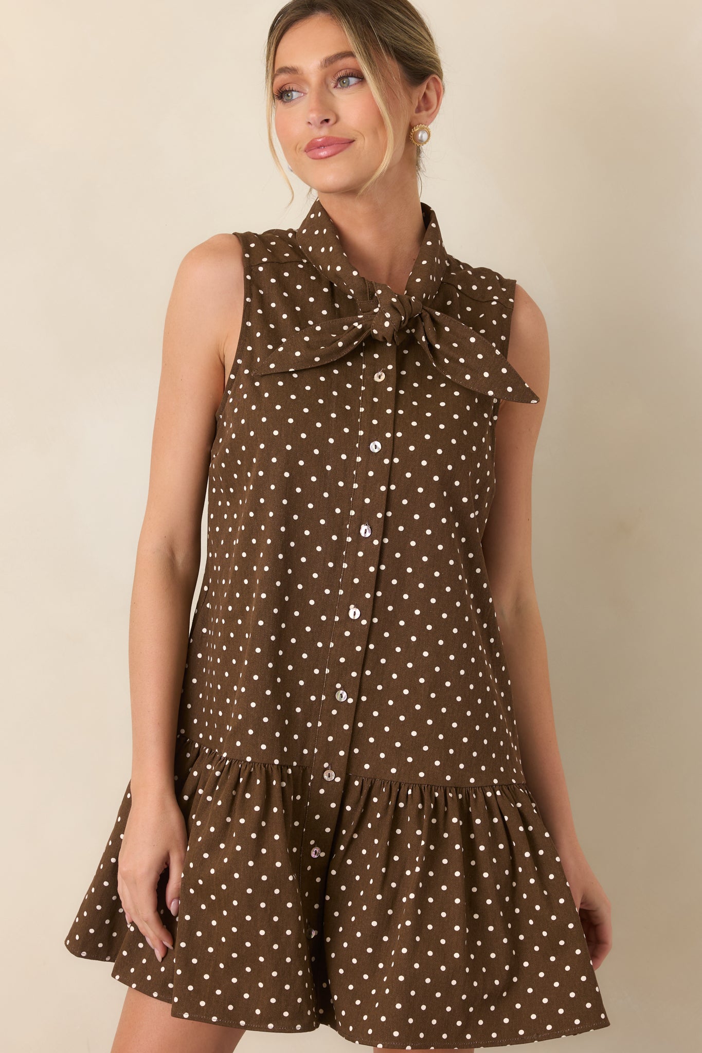 Close view of the ivory polka dot dress highlighting the self-tie neckline and functional button-front closure.