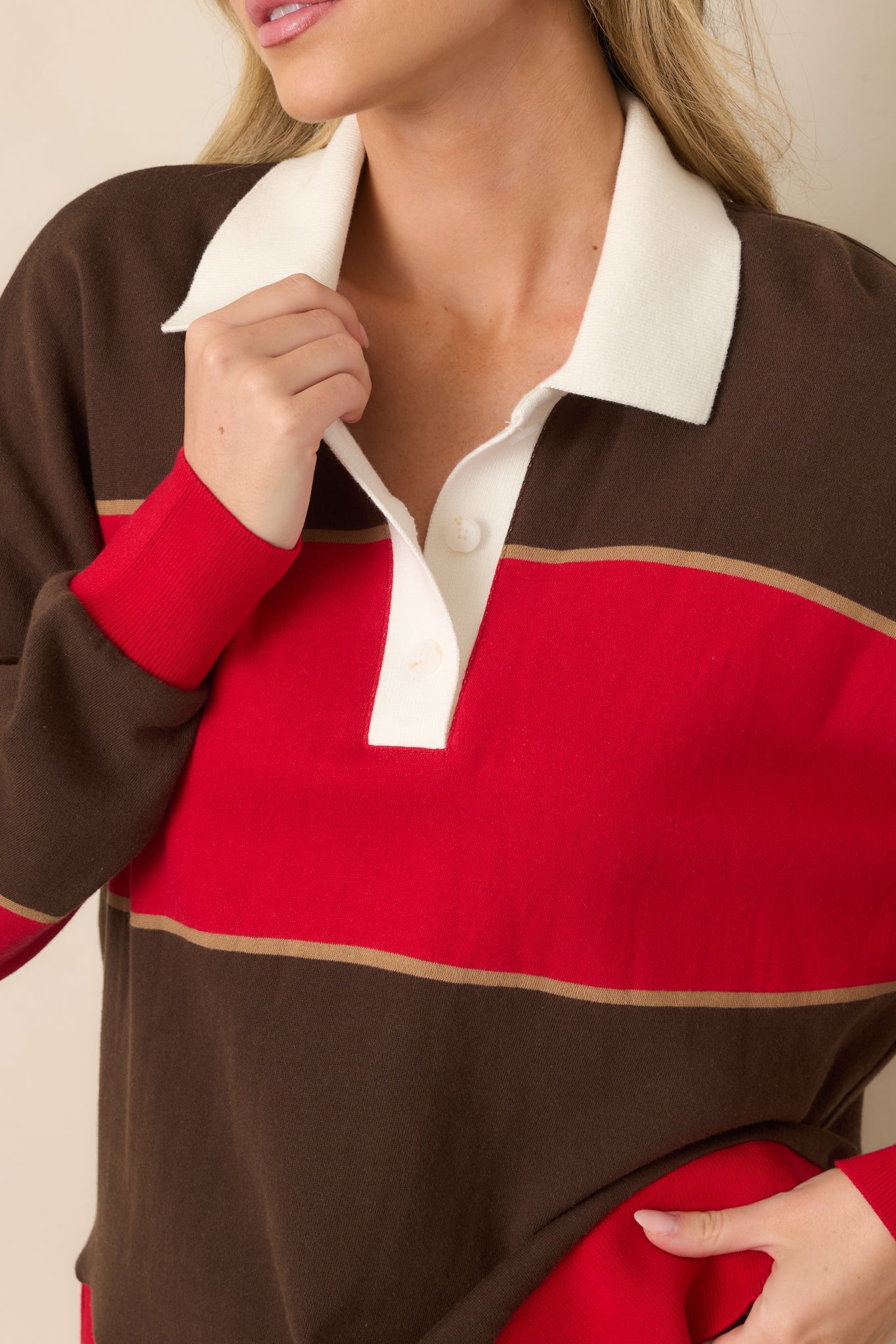 Close-up of the ivory polo collar and button placket, showcasing the contrasting red and chocolate brown striped colorblock pattern.