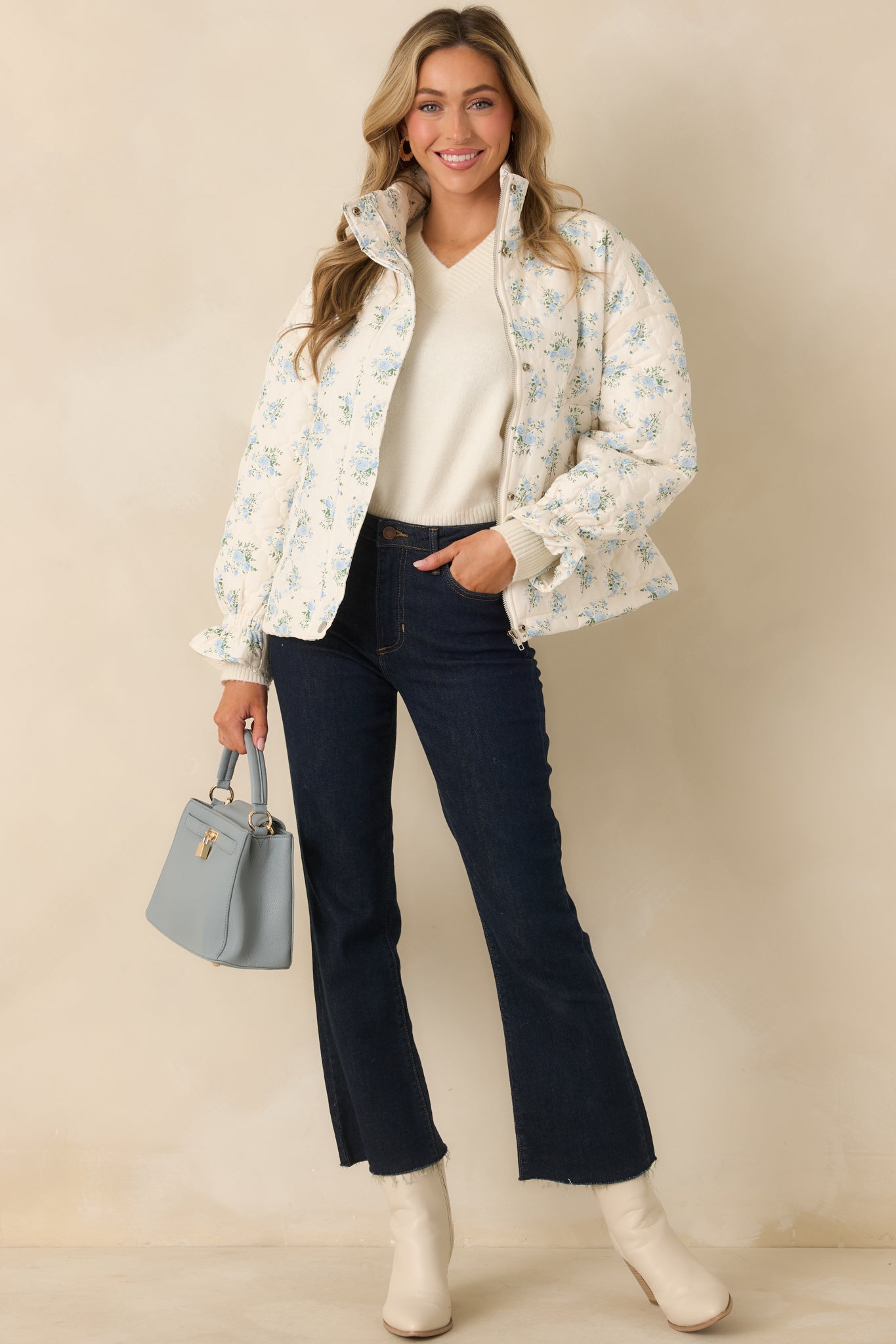 Ivory quilted jacket with allover soft blue floral print and subtle green accents, featuring a high neckline and snap-button front closure.
