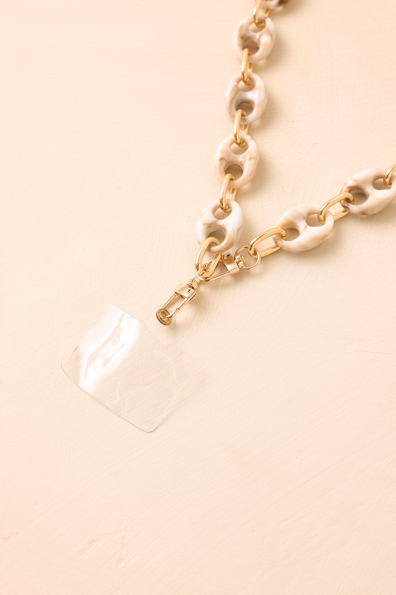 Ivory resin link phone accessory featuring bold rounded shapes and polished gold-tone accents.