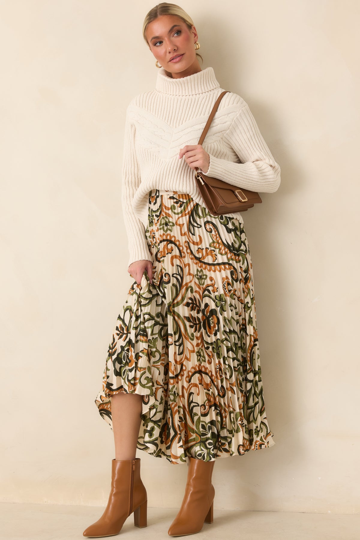 Ivory ribbed sweater with a fold-over turtleneck, chevron cable knit detailing, and a relaxed silhouette.