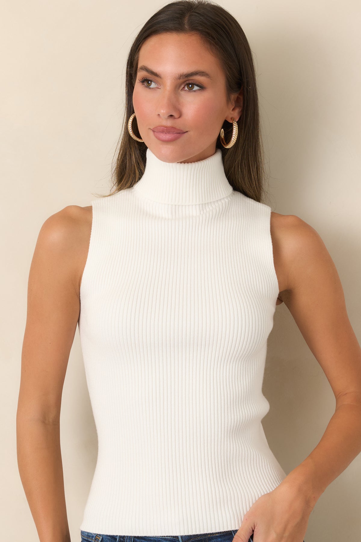 Ivory ribbed knit top highlighting the fitted silhouette and high fold-over neckline.