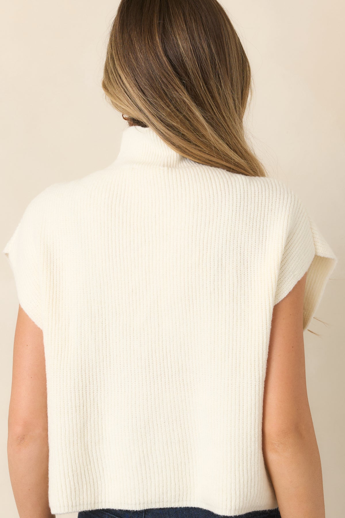 Rear view of the ivory ribbed knit top showcasing the relaxed silhouette, mock neckline, cap sleeves, and clean hemline.