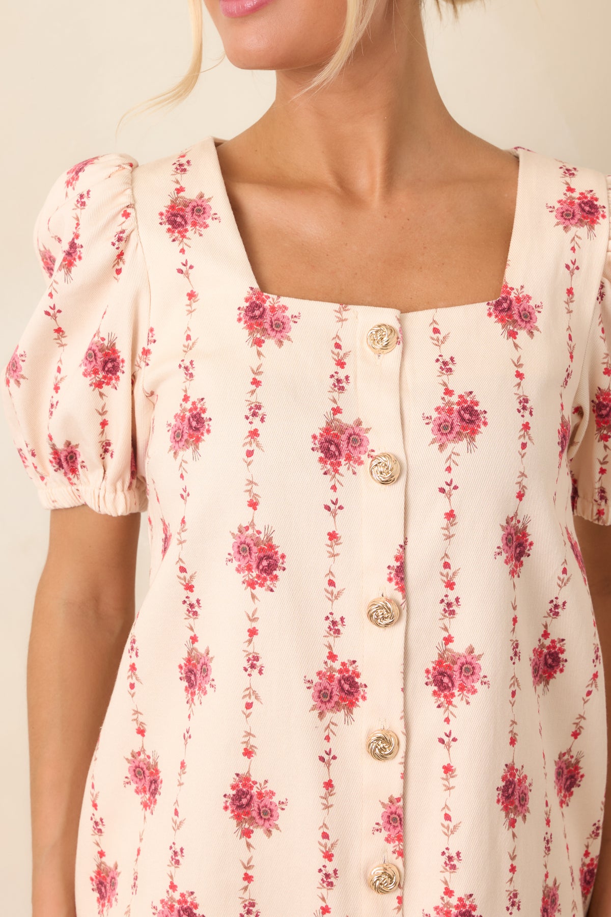 Close-up highlights the rose bouquet print, trailing vines, square neckline, and polished gold-tone button detailing.