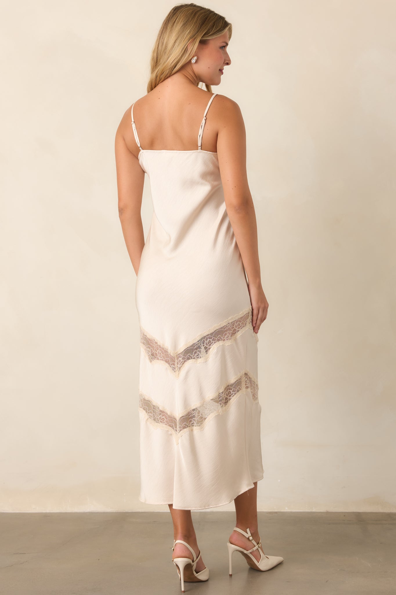 Rear view of the ivory satin dress showcasing its slender straps, fluid shape, and softly draped silhouette.