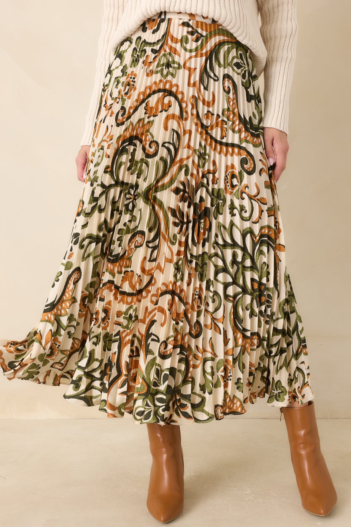 Olive green and camel paisley motifs decorate the ivory satin skirt across its finely pleated fabric.