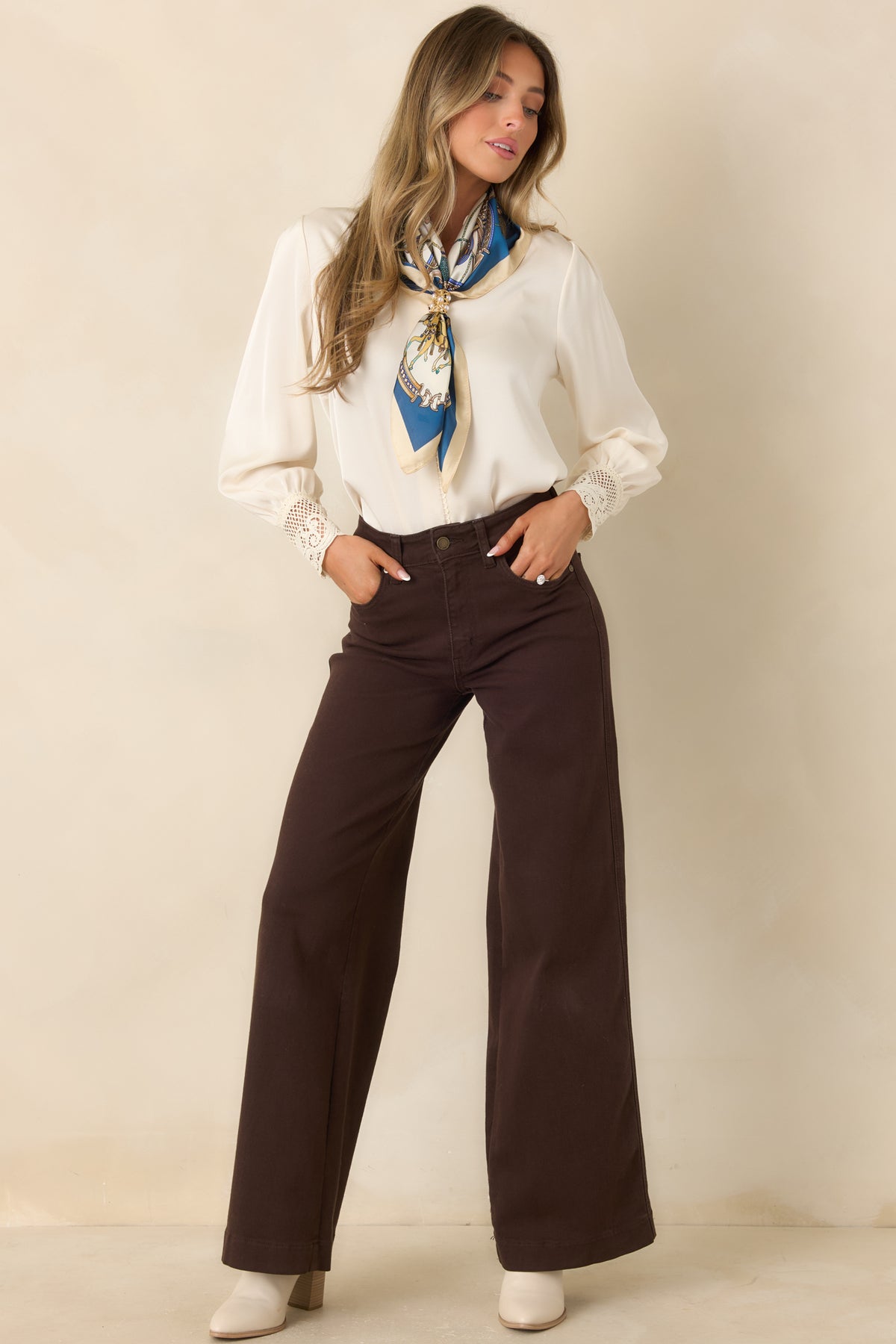 Ivory satin blouse with a split V-neckline, delicate loop trim, long sleeves, and sheer scalloped lace cuffs.