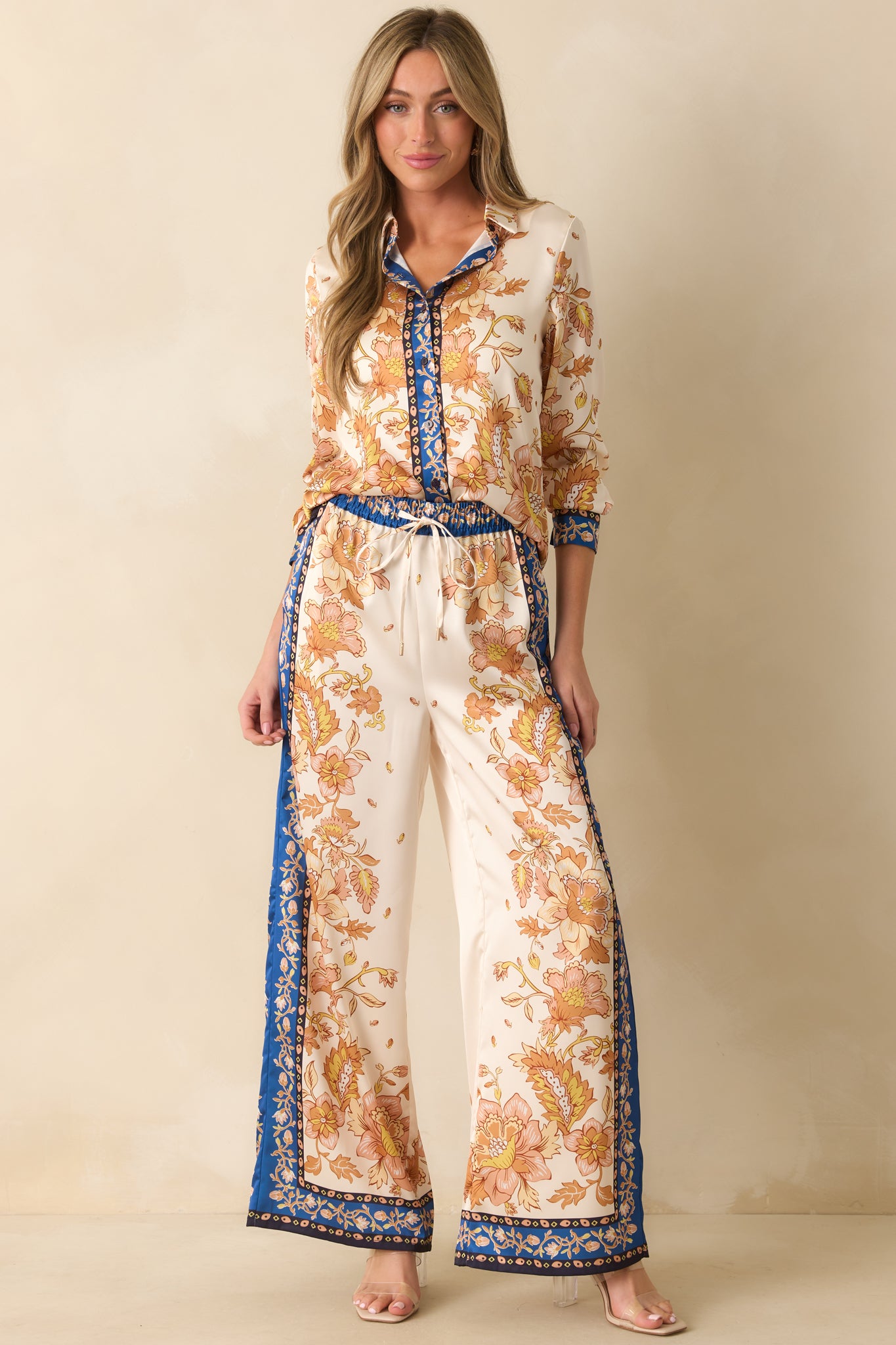 Ivory satin top with collared neckline, golden yellow floral scarf-style print, and contrast navy border trim.
