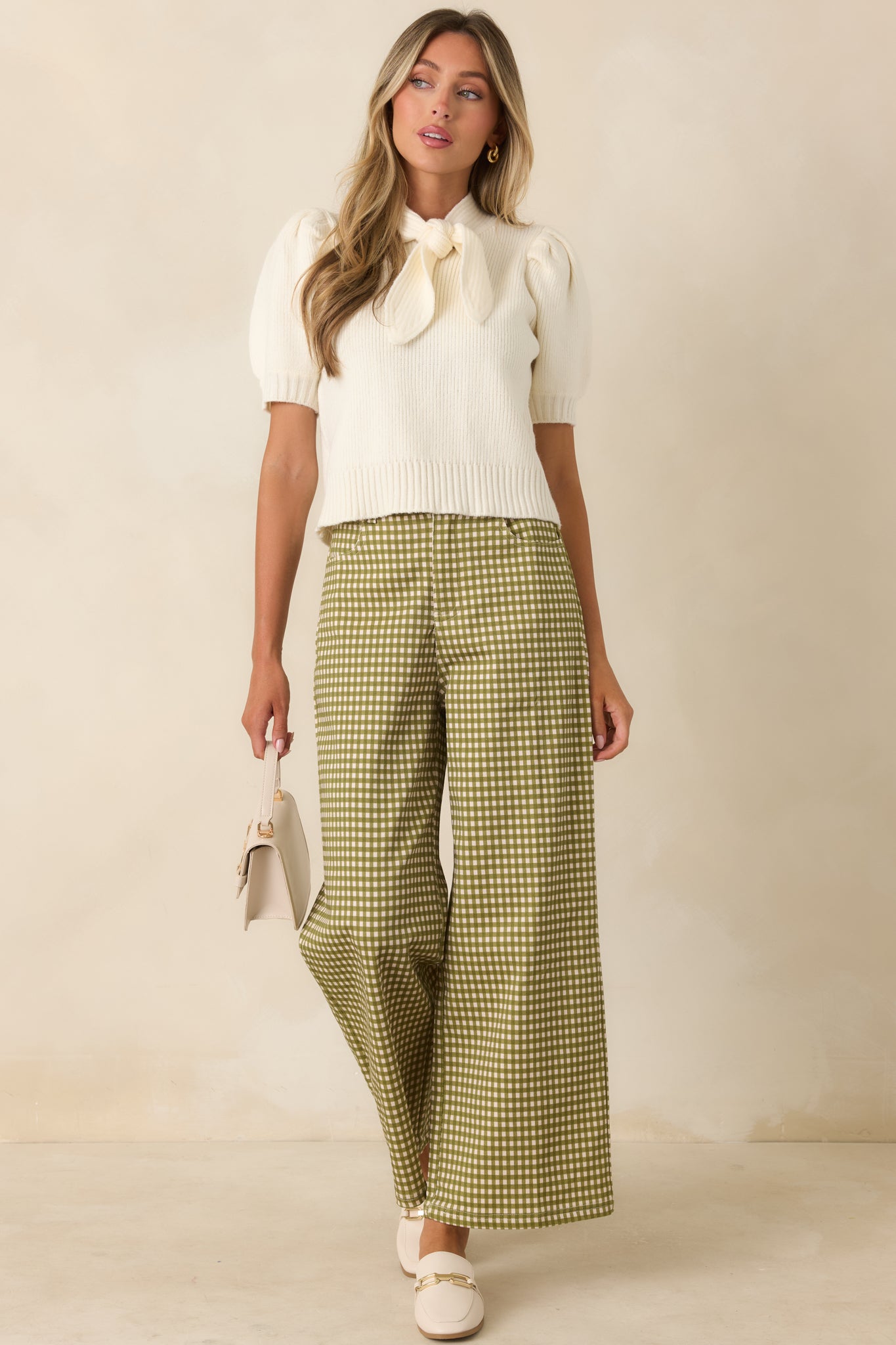 Stretch ribbed ivory knit top designed with a statement self-tie neckline, long puff sleeves, and a structured ribbed hem.