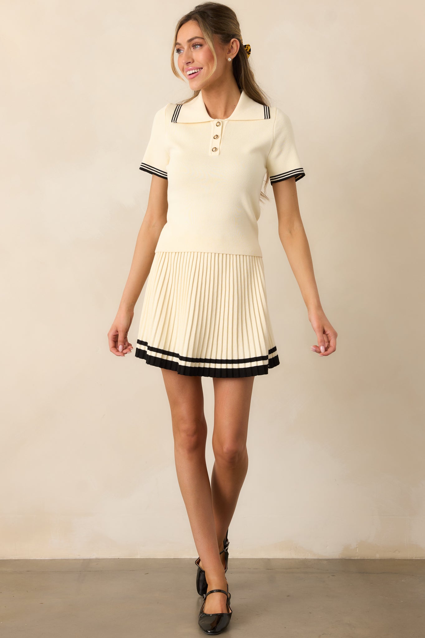 Front view of the ivory shirt showcasing a structured collar, short sleeves, and bold black stripe accents for a classic touch.