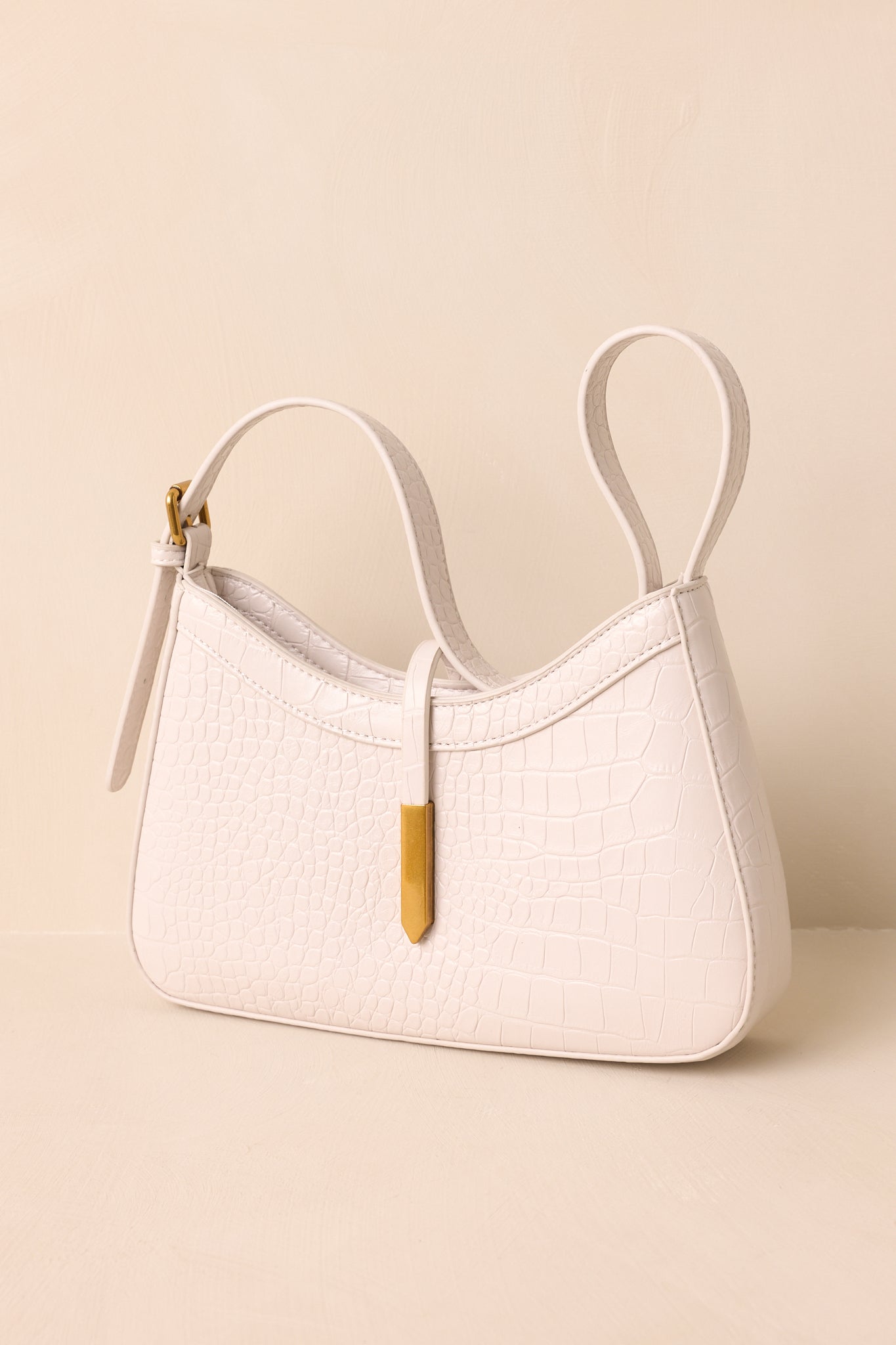 Ivory shoulder bag with structured croc-embossed faux leather, adjustable strap, and rectangular gold-accented closure.