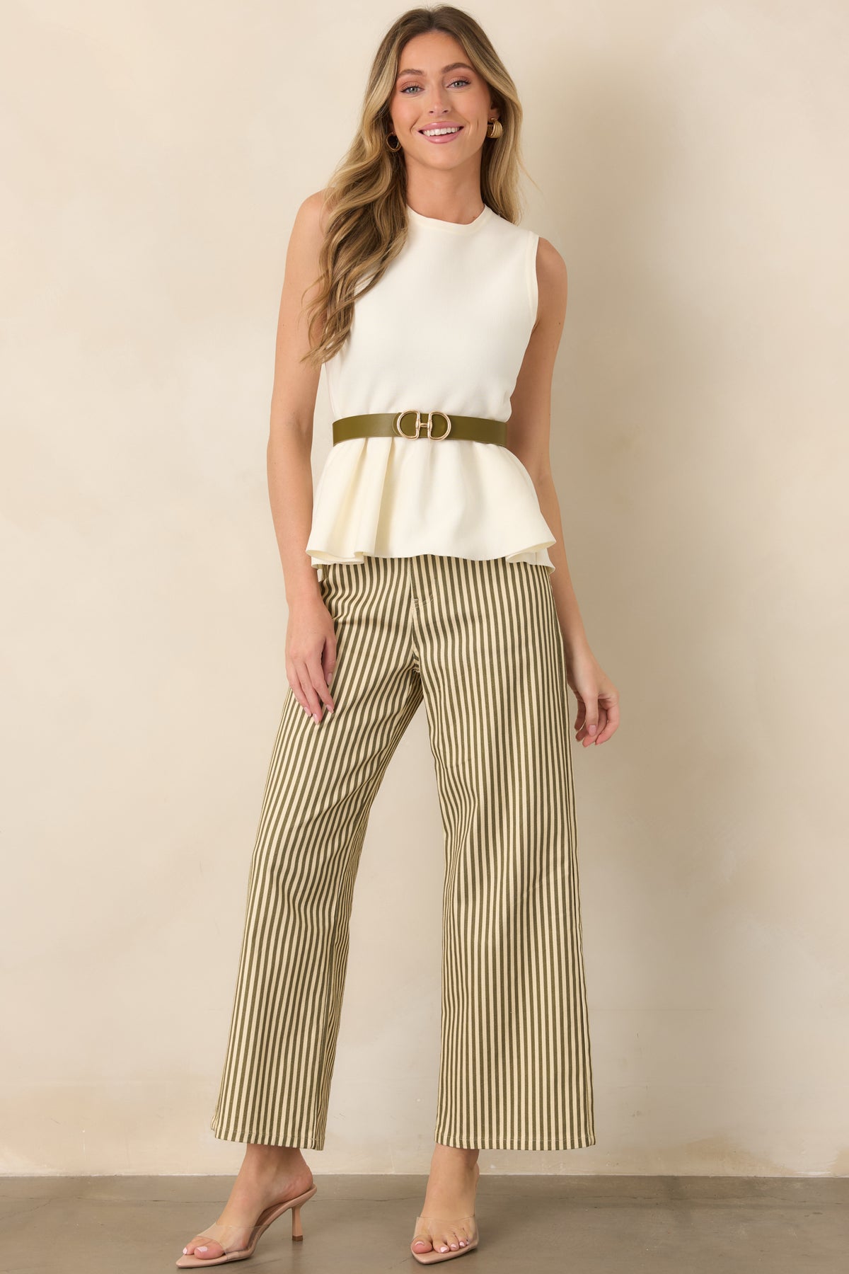 Ivory sleeveless knit top with a smooth fitted bodice, classic round neckline, defined waist, and softly flared peplum shape.