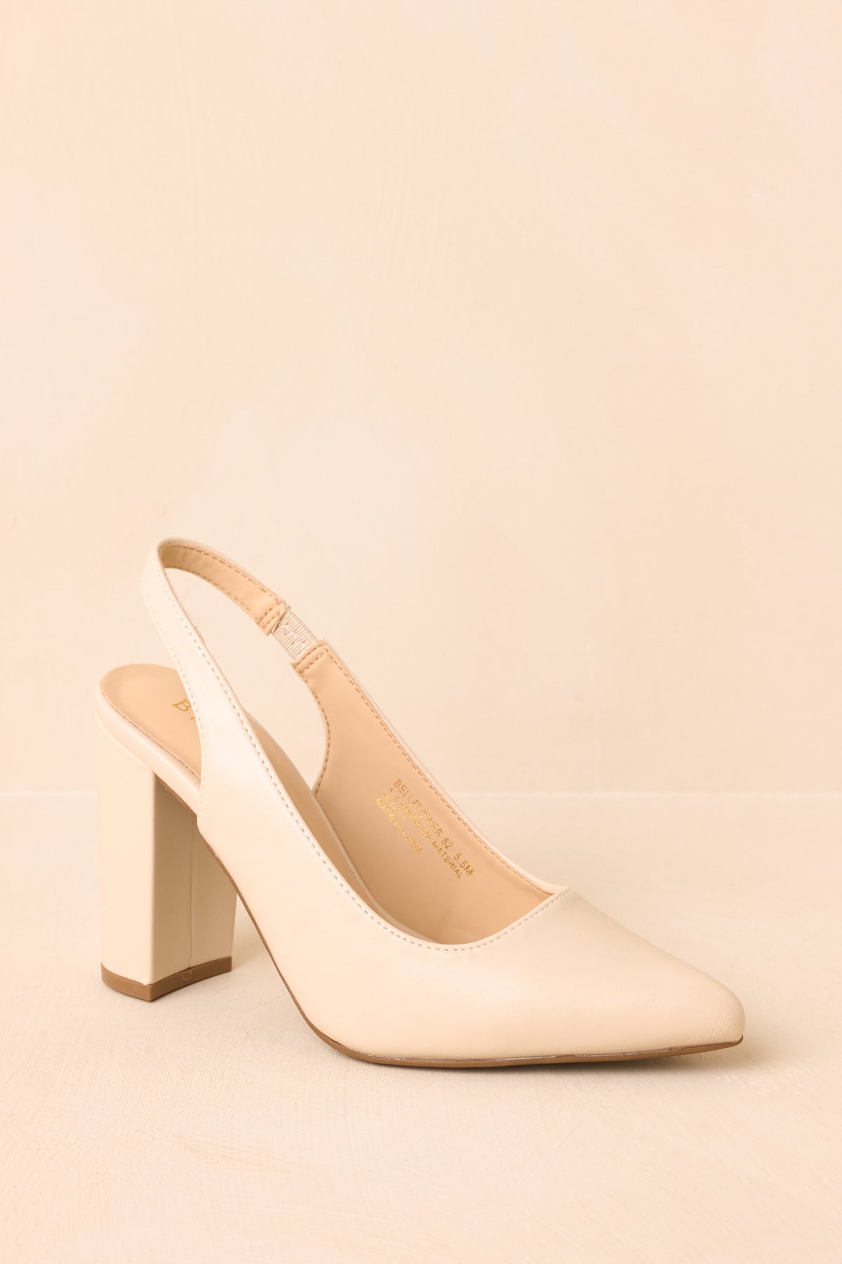 Ivory slingback heels shown from an angled view, highlighting the pointed toes and tall block heels.