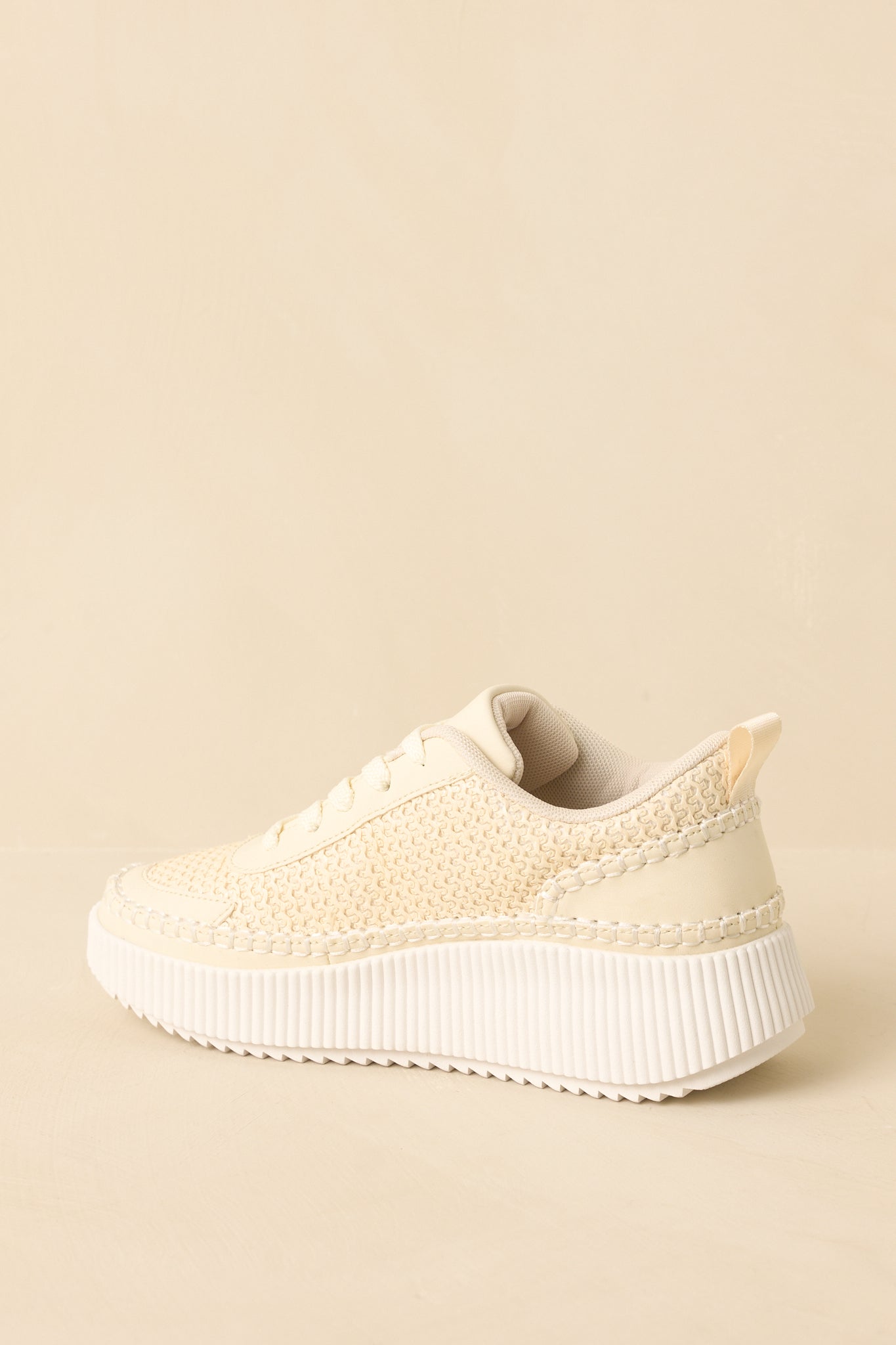 Ivory knit sneakers presented from a low angle to emphasize the supportive platform sole.