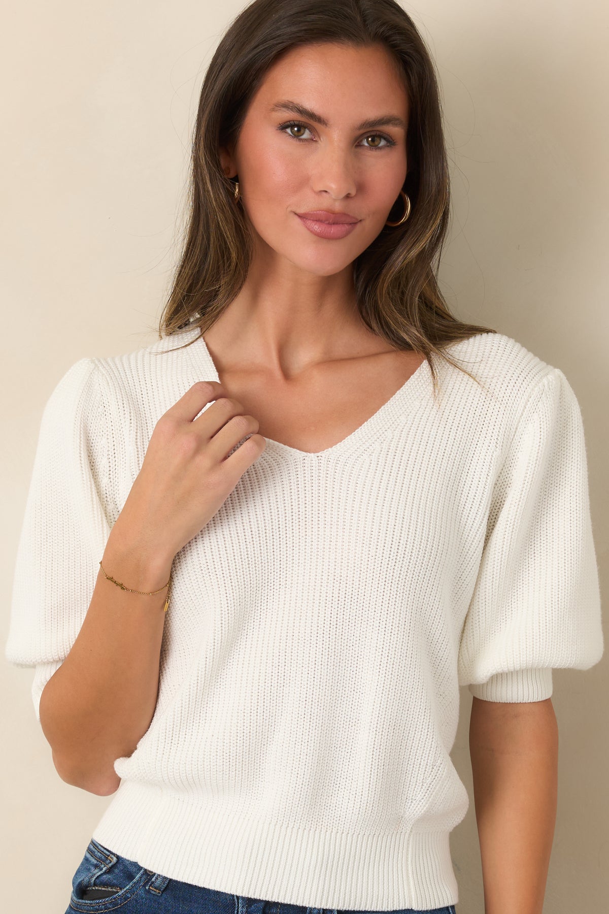 Softly structured ivory top featuring a clean V-neckline and gently gathered sleeves.