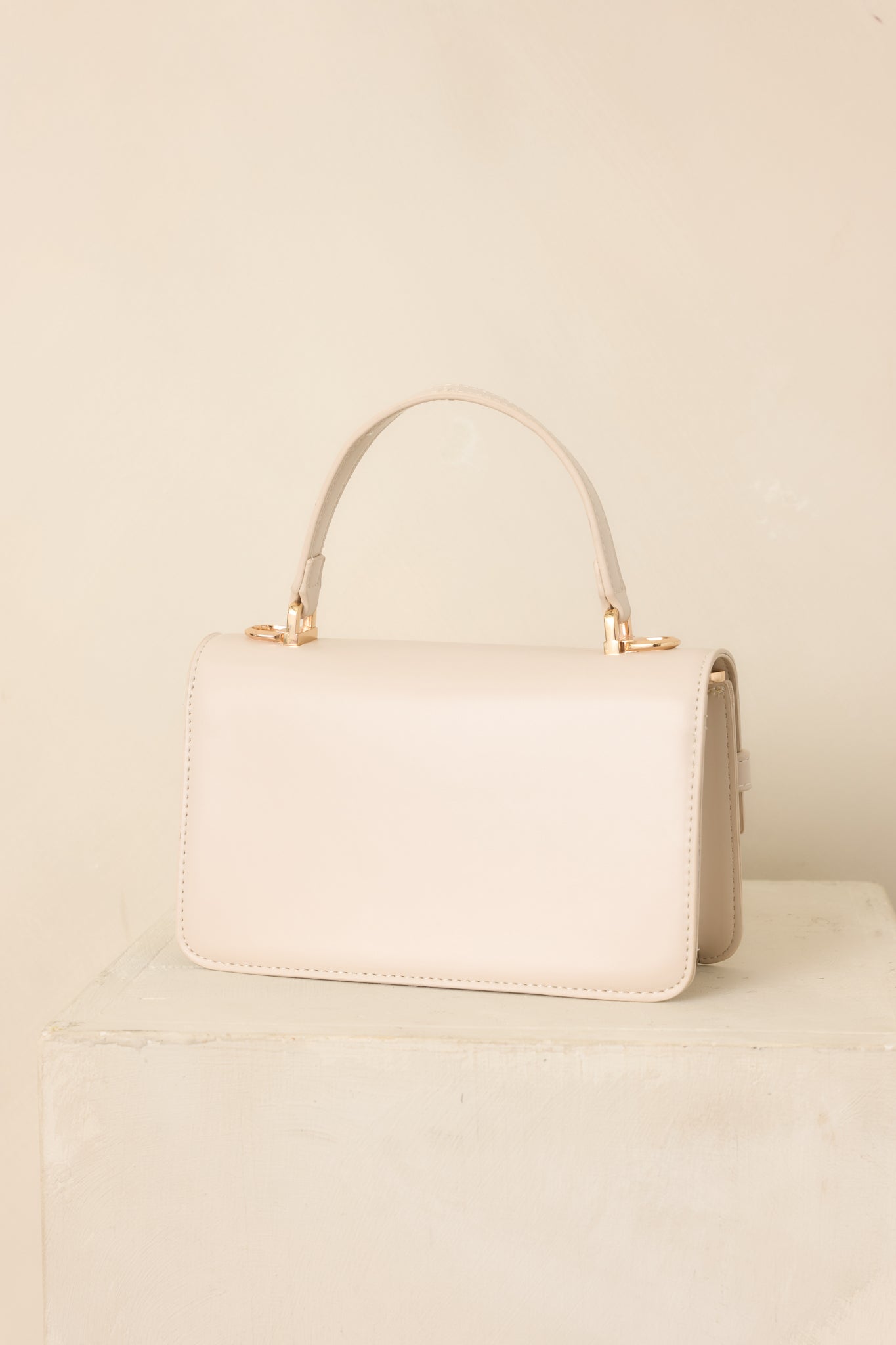 Rear view of the ivory structured handbag showcasing its smooth faux leather exterior, clean rectangular shape, and detachable shoulder strap.