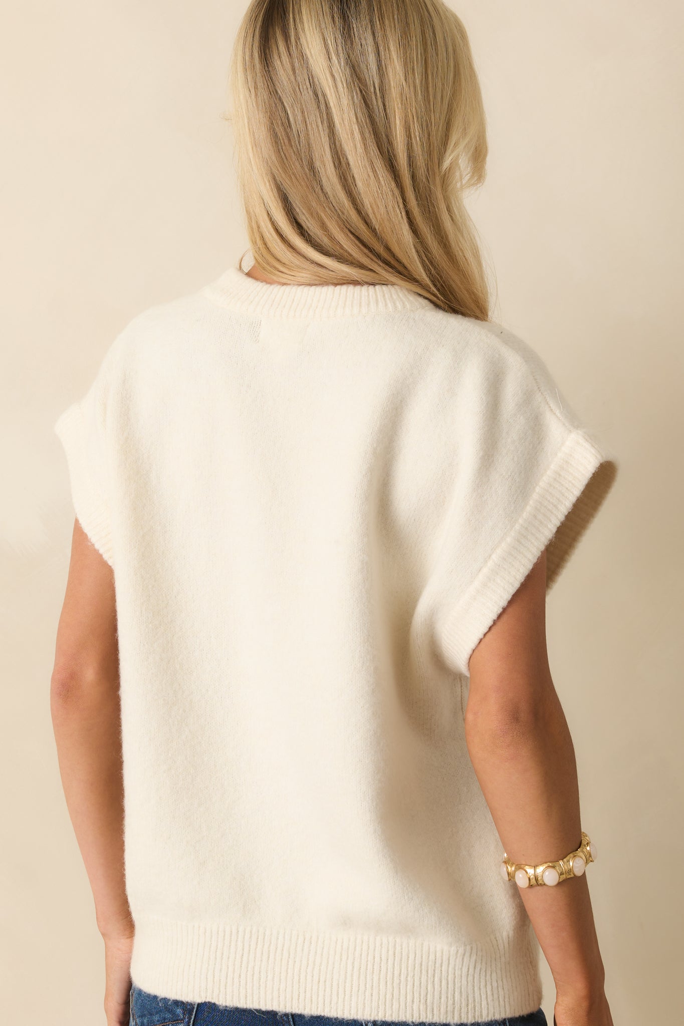 A back view of the ivory sweater showing its oversized fit and straight hemline.