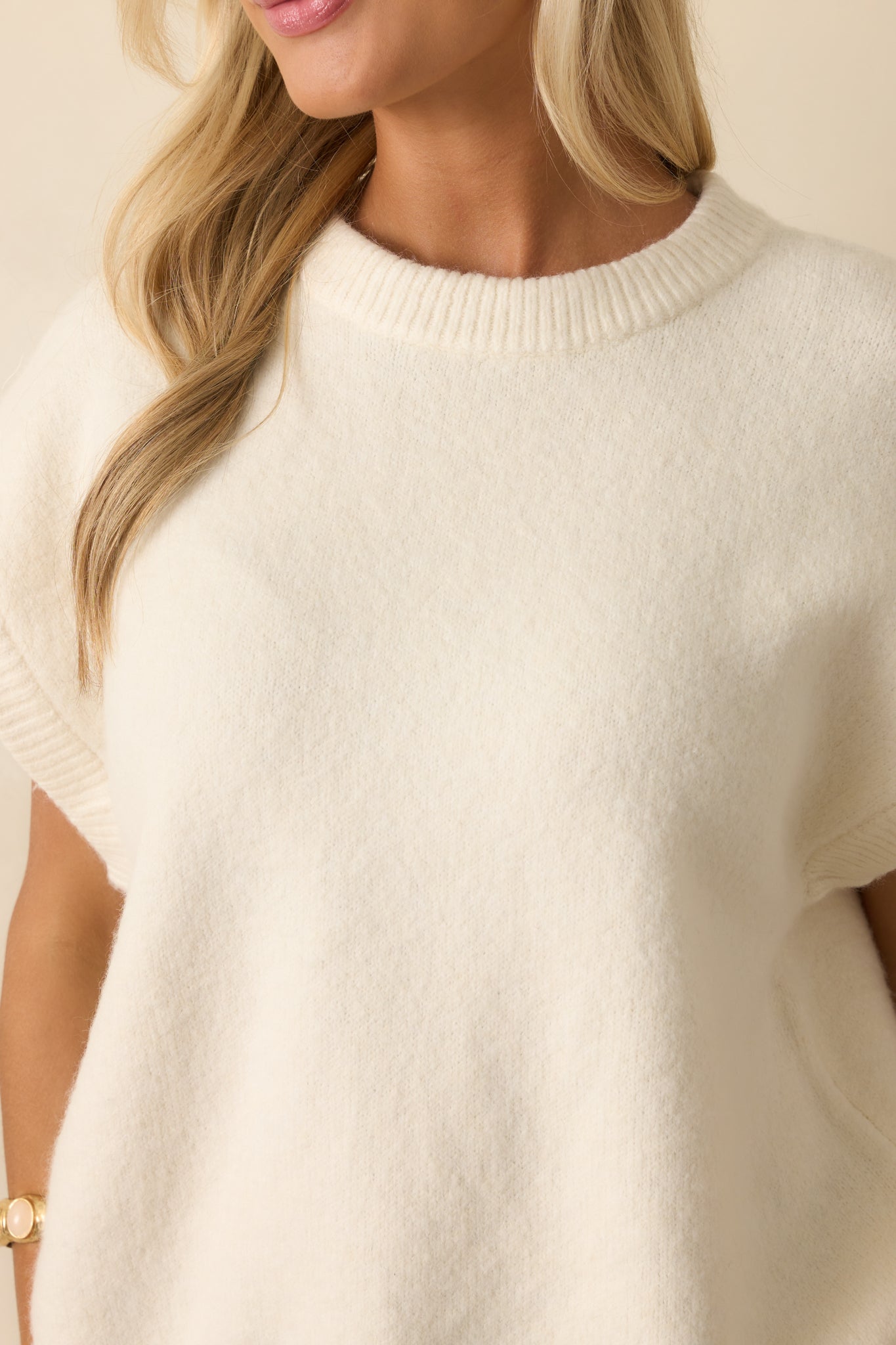 Detailed look at the ribbed knit trim and texture of the ivory sweater.
